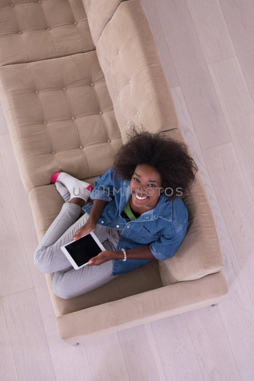 Young african american woman at home relaxing in her luxury lliving room reading a digital tablet PC surf internet and work top view