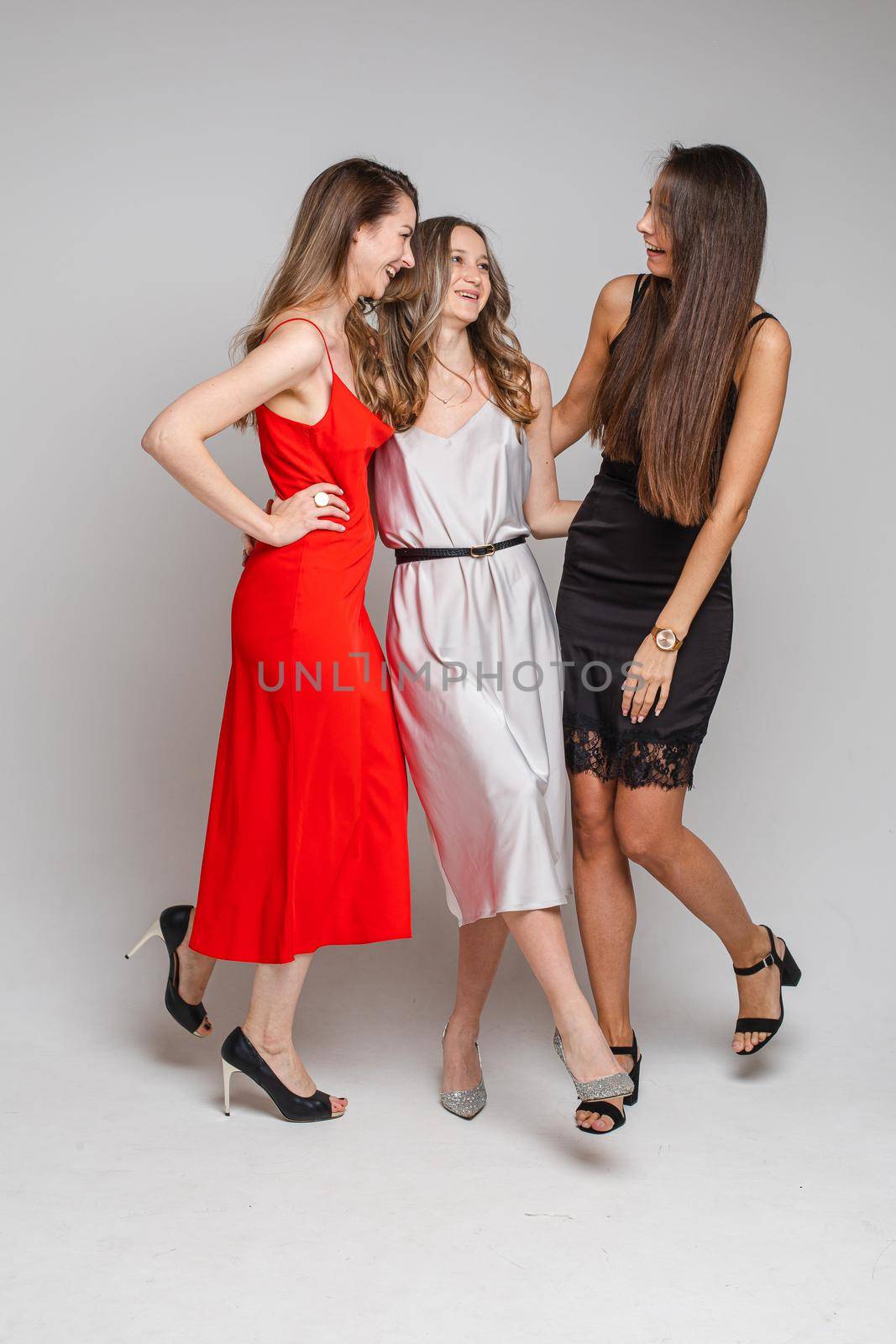 Laughing embracing women in cocktail dresses. by StudioLucky