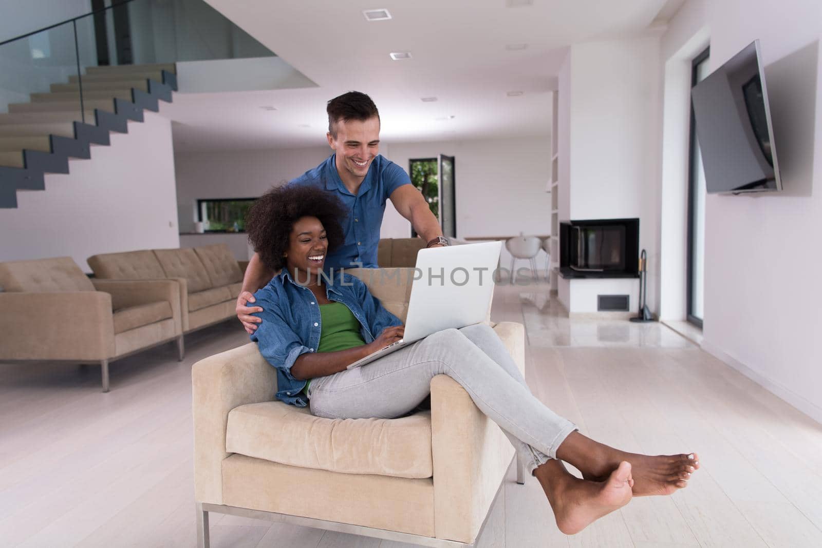 multiethnic couple on an armchair with a laptop by dotshock