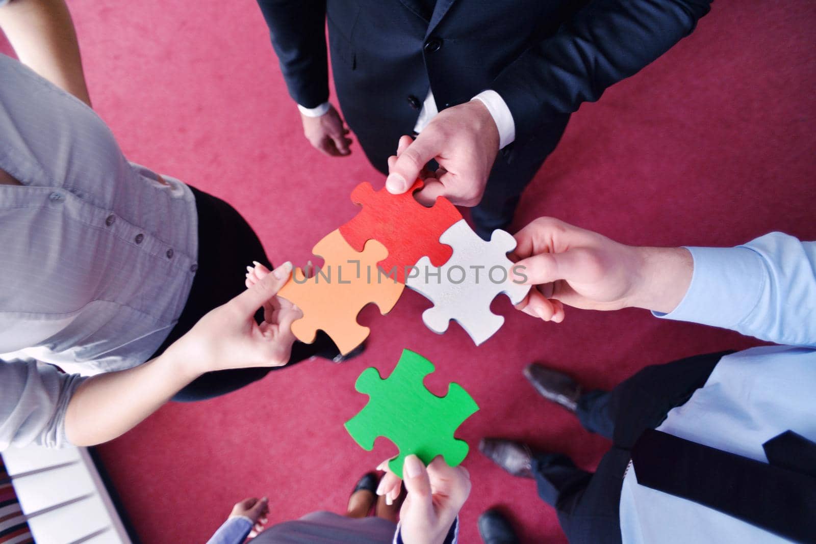 Group of business people assembling jigsaw puzzle and represent team support and help concept