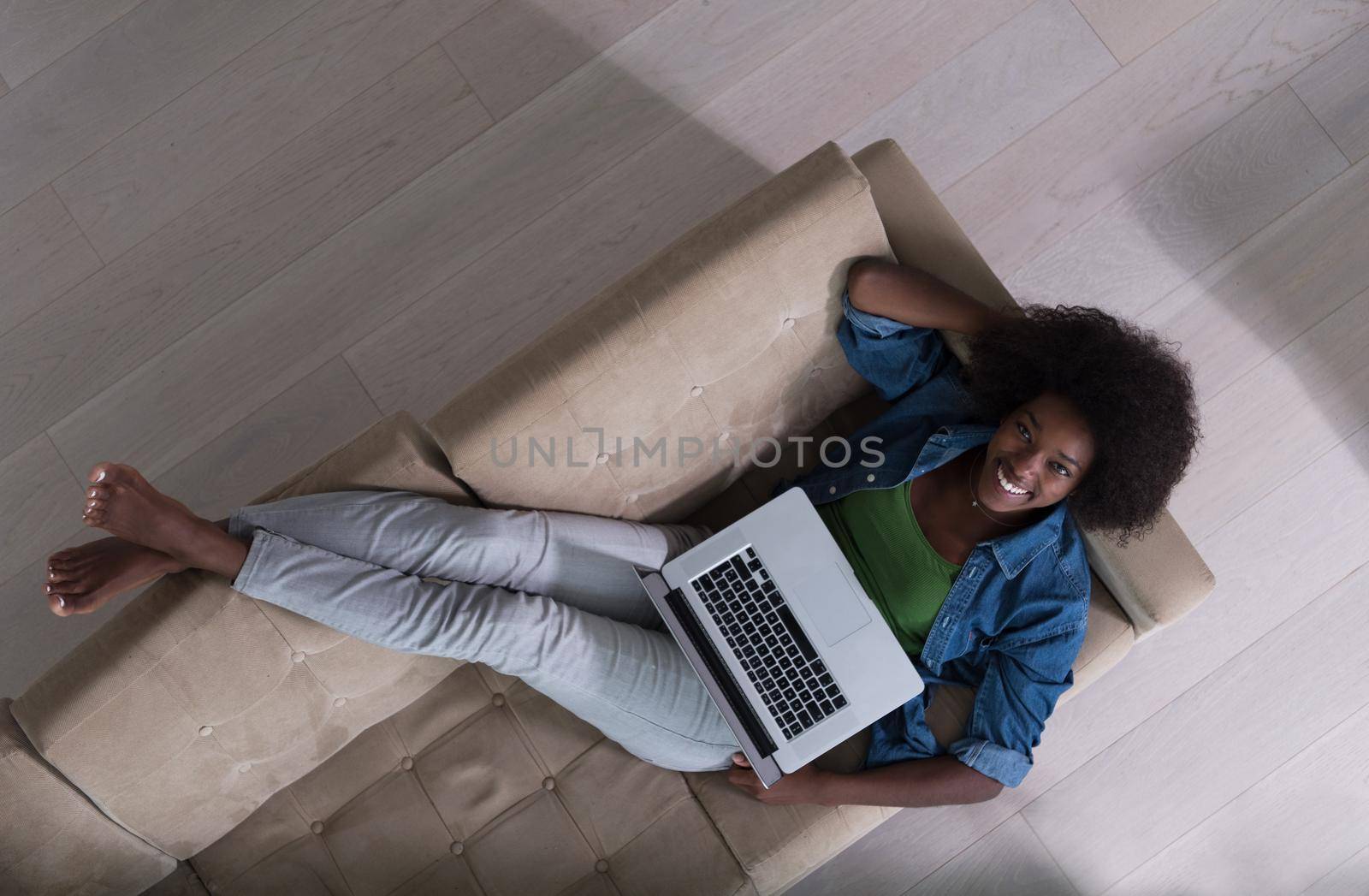 African American woman using laptop on sofa top view by dotshock