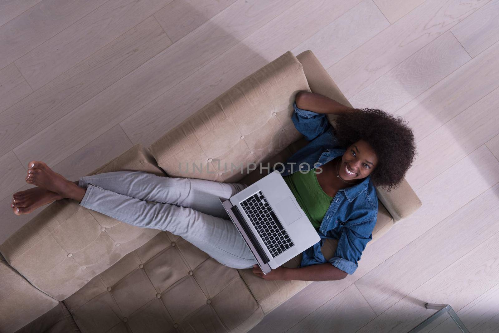African American woman using laptop on sofa top view by dotshock