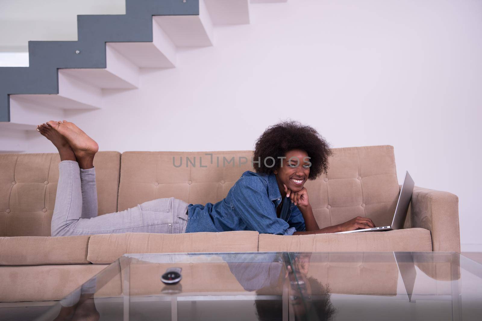 African American woman using laptop on sofa by dotshock