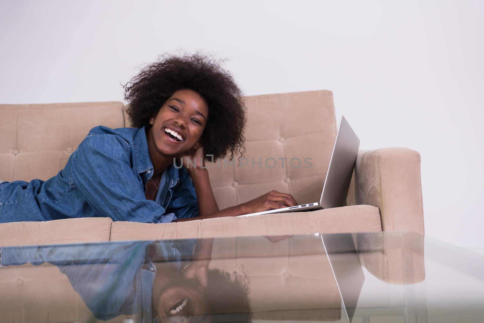 African American woman using laptop on sofa by dotshock