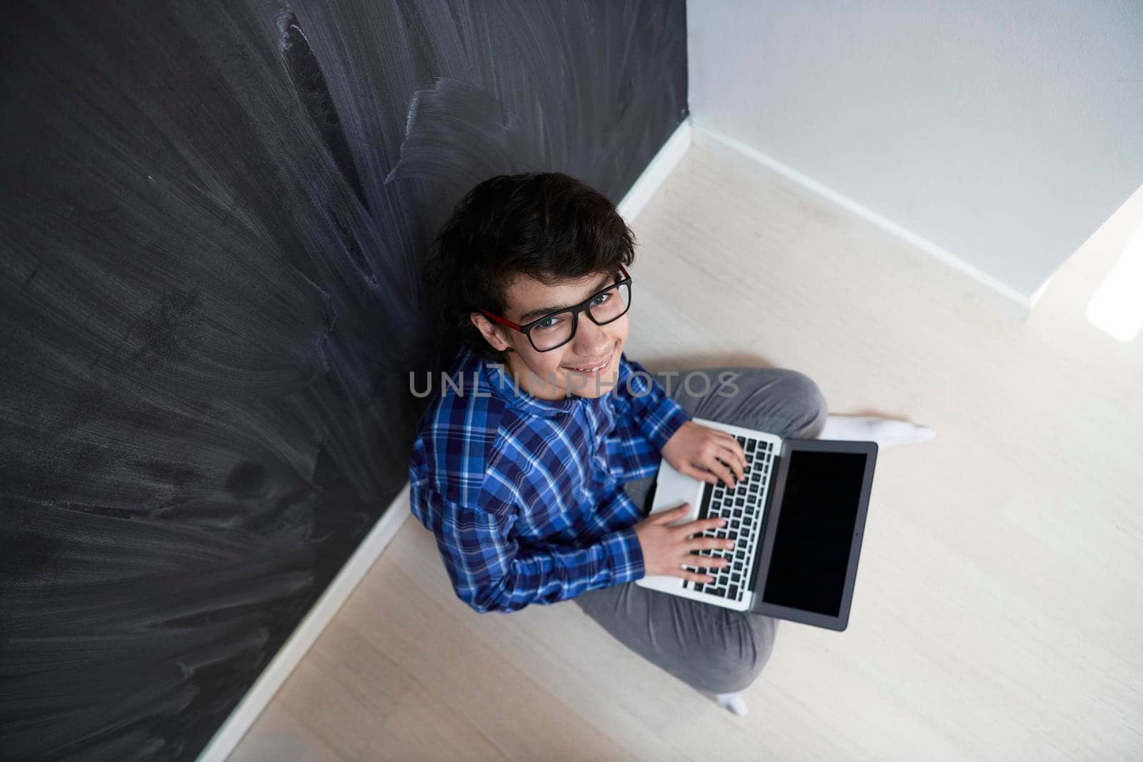 Arab teenager using laptop to work on homework and watch online education while staying at home cause coronavirus pandemic quarantine