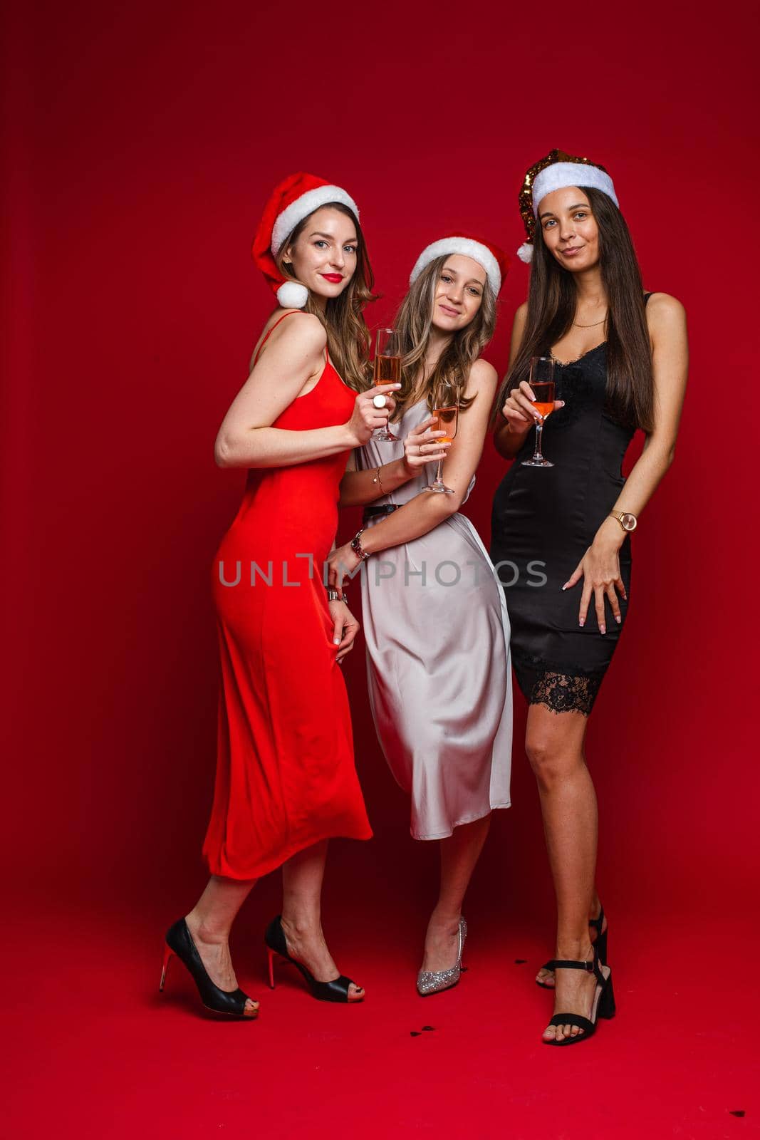 beautiful female friends in dresses with champagne, isolated on white background