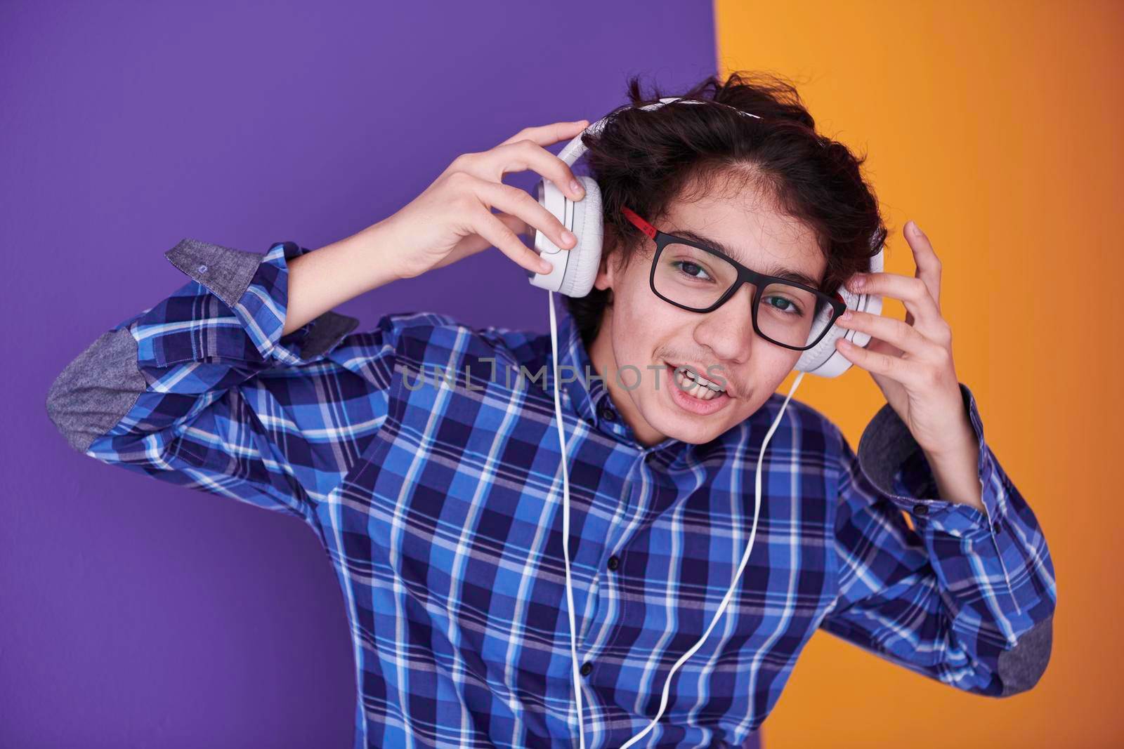 Teenage Boy Wearing Headphones And Listening To Music purple background