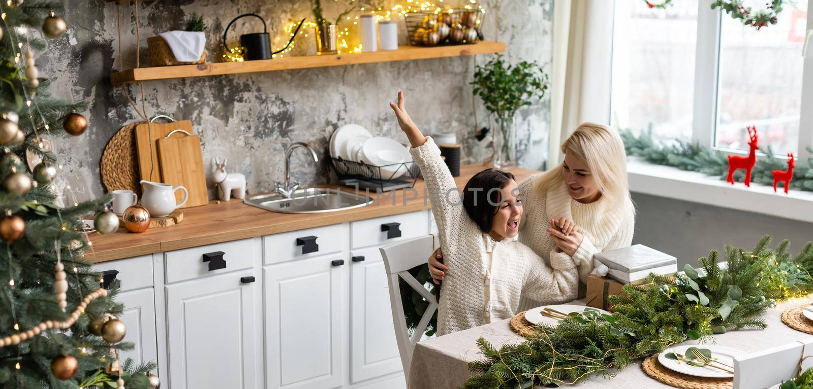 Beautiful young family enjoying their holiday time together, decorating Christmas tree, arranging the christmas lights and having fun.