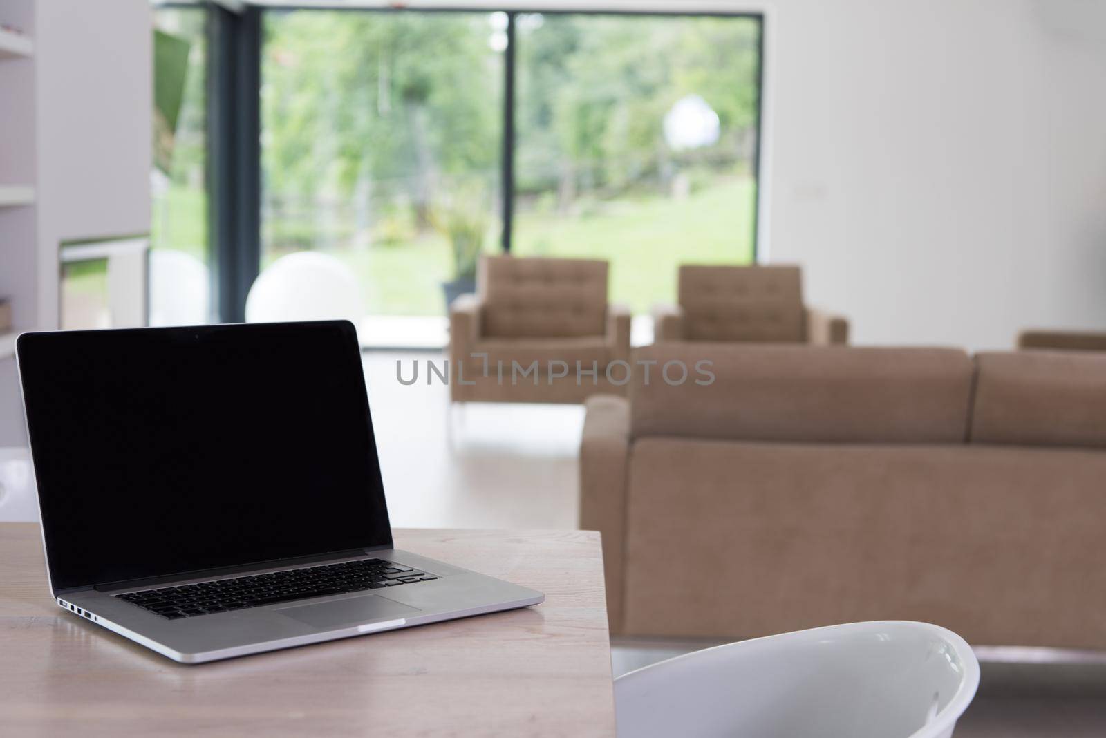 Notebook with blank screen on table in luxury living room.