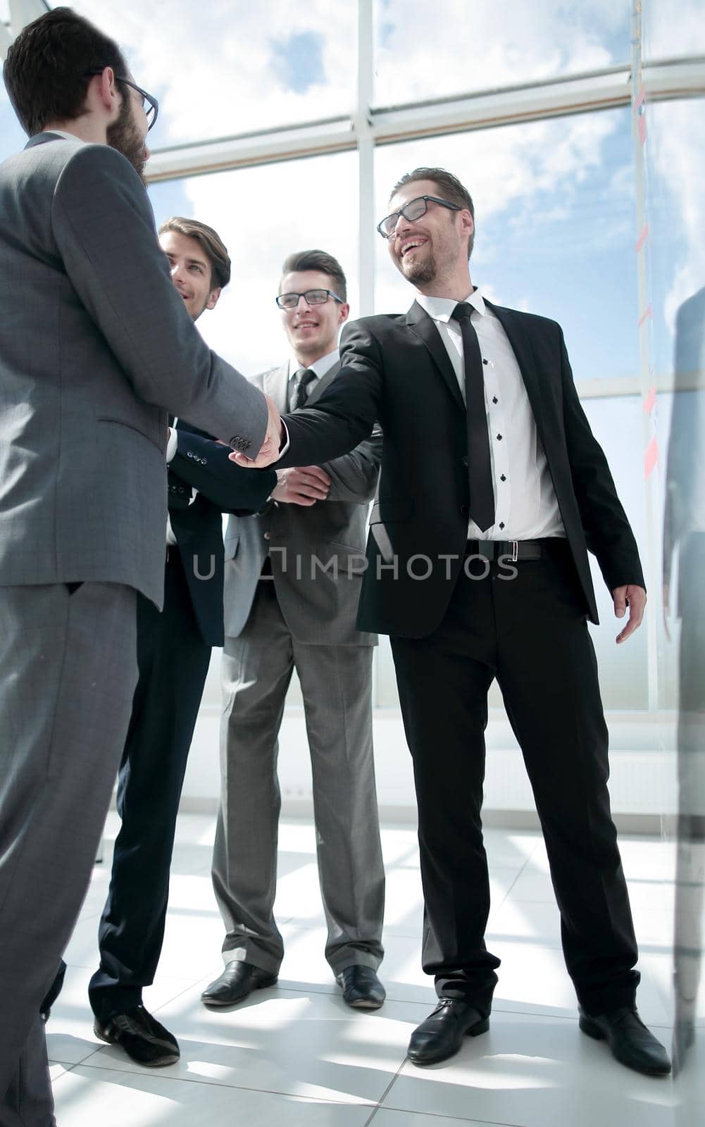 handshake of serious business partners standing in the office by asdf