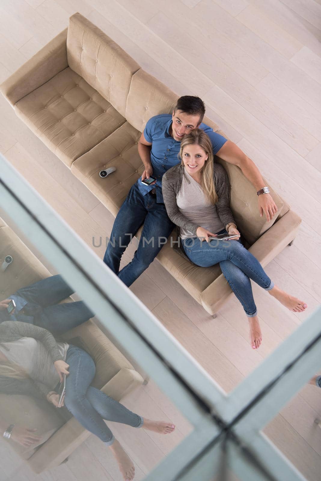 Young couple sitting on a sofa in the luxury living room, using a tablet computer top view