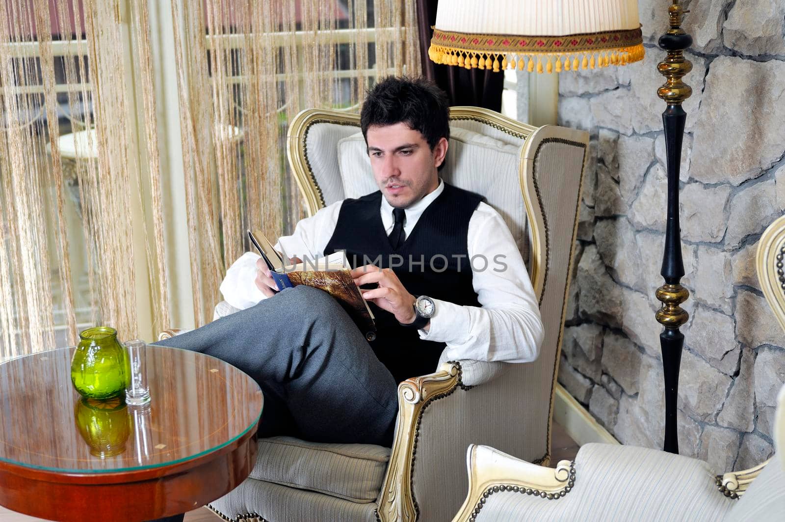 young man reading book and relaxing in luxury indoor