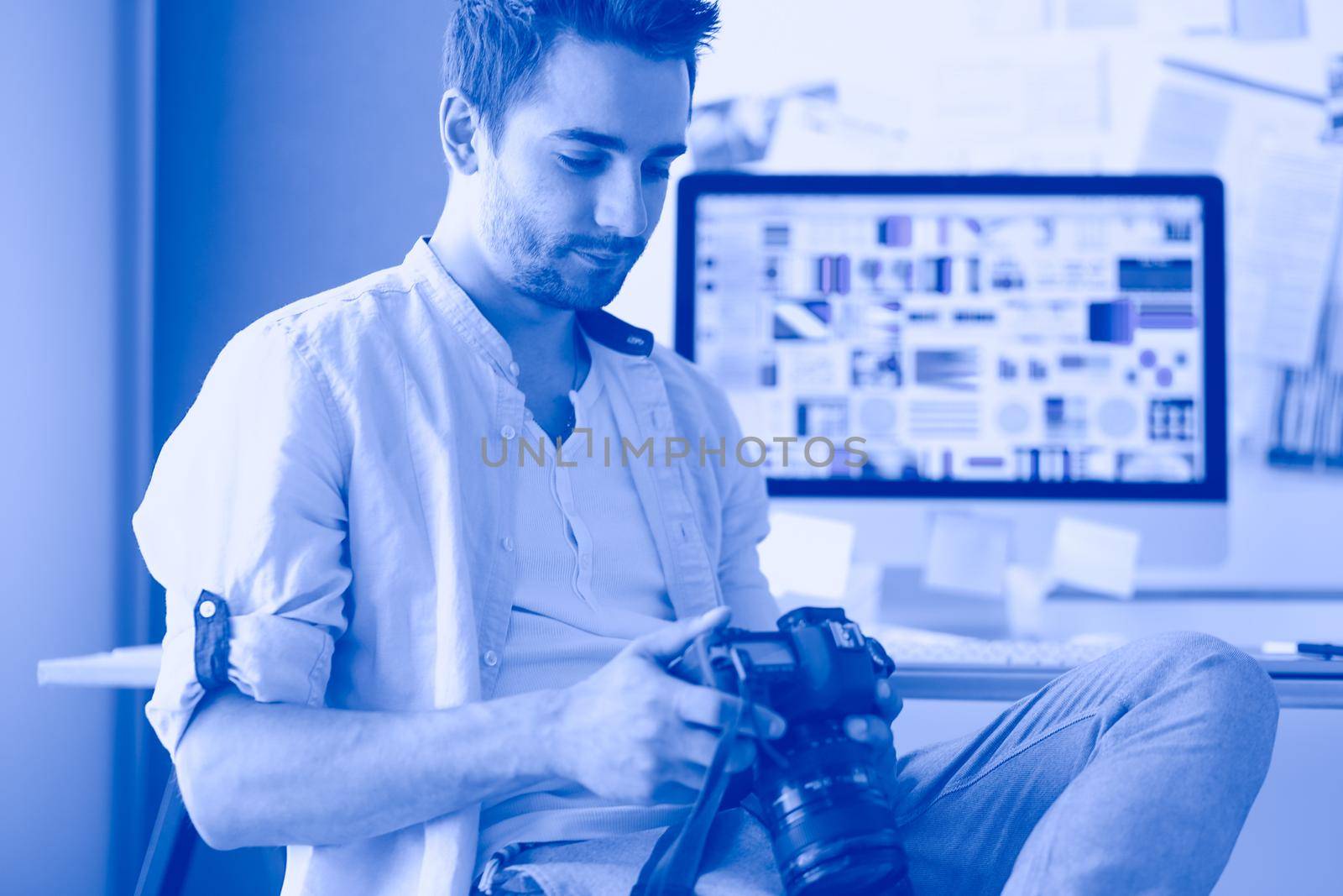 Portrait of young designer sitting at graphic studio in front of laptop and computer while working online