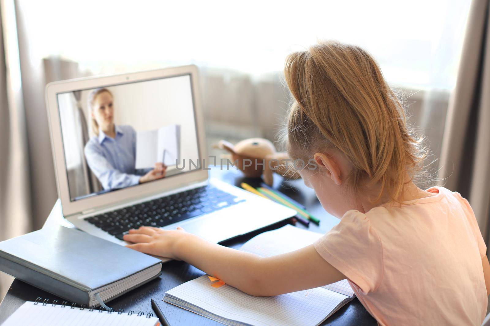 Distance learning. Cheerful little girl using laptop computer studying through online e-learning system