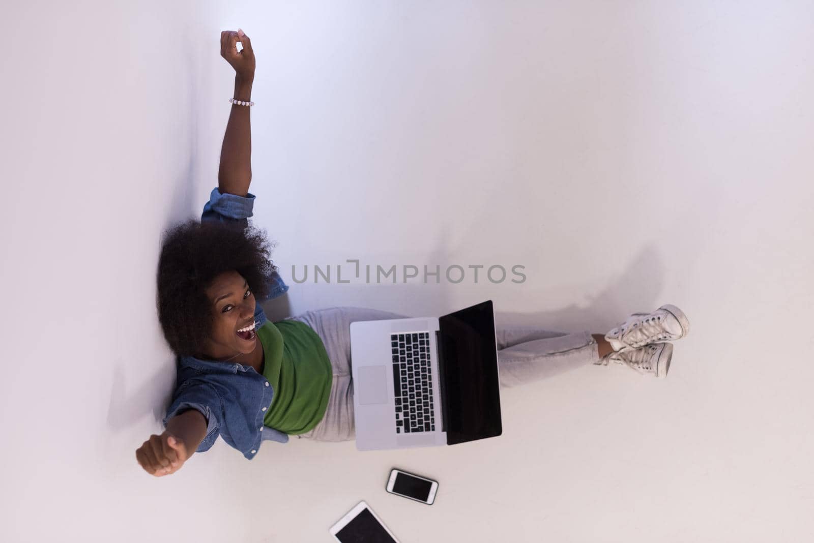 african american woman sitting on floor with laptop top view by dotshock