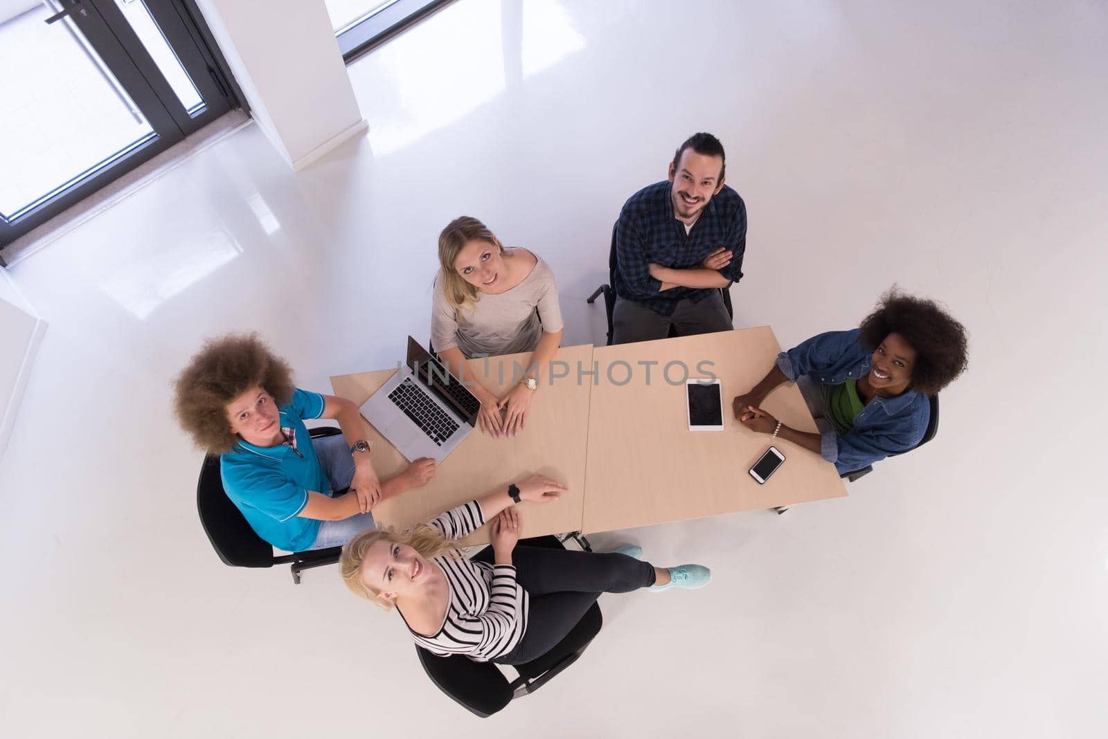 Multiethnic startup business team on meeting in modern bright office interior brainstorming, working on laptop and tablet computer top view