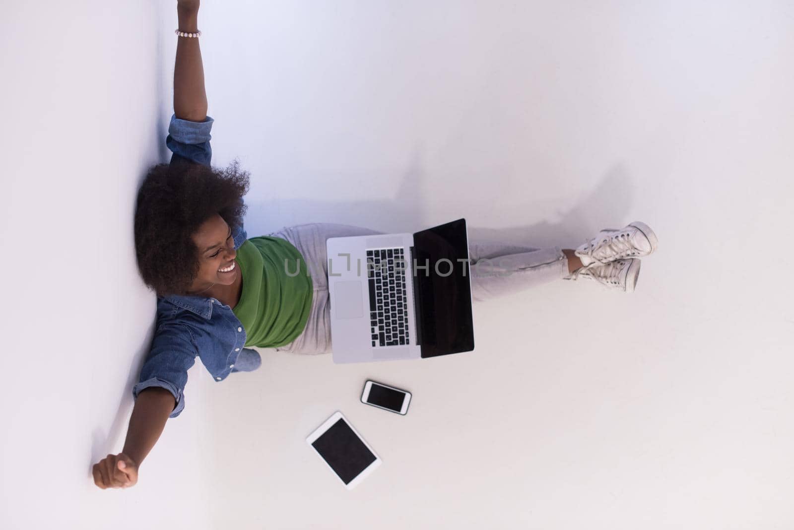 african american woman sitting on floor with laptop top view by dotshock