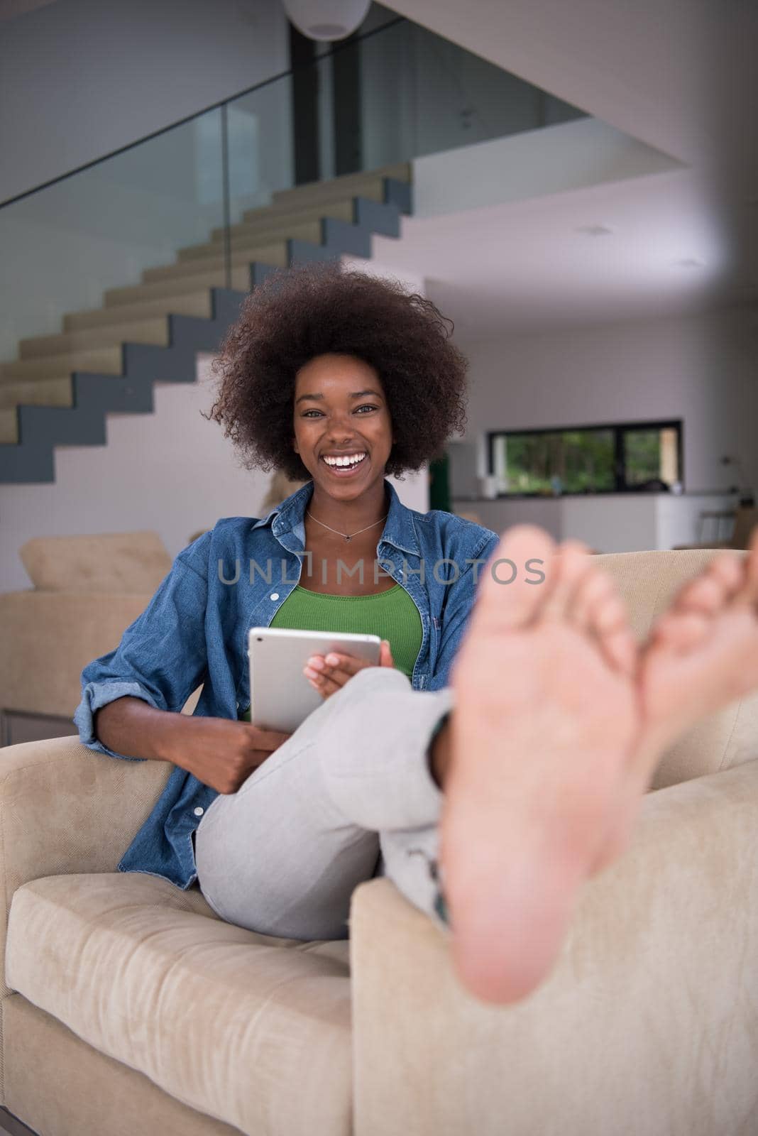 Young african american woman at home relaxing in her luxury lliving room reading a digital tablet PC surf internet and work