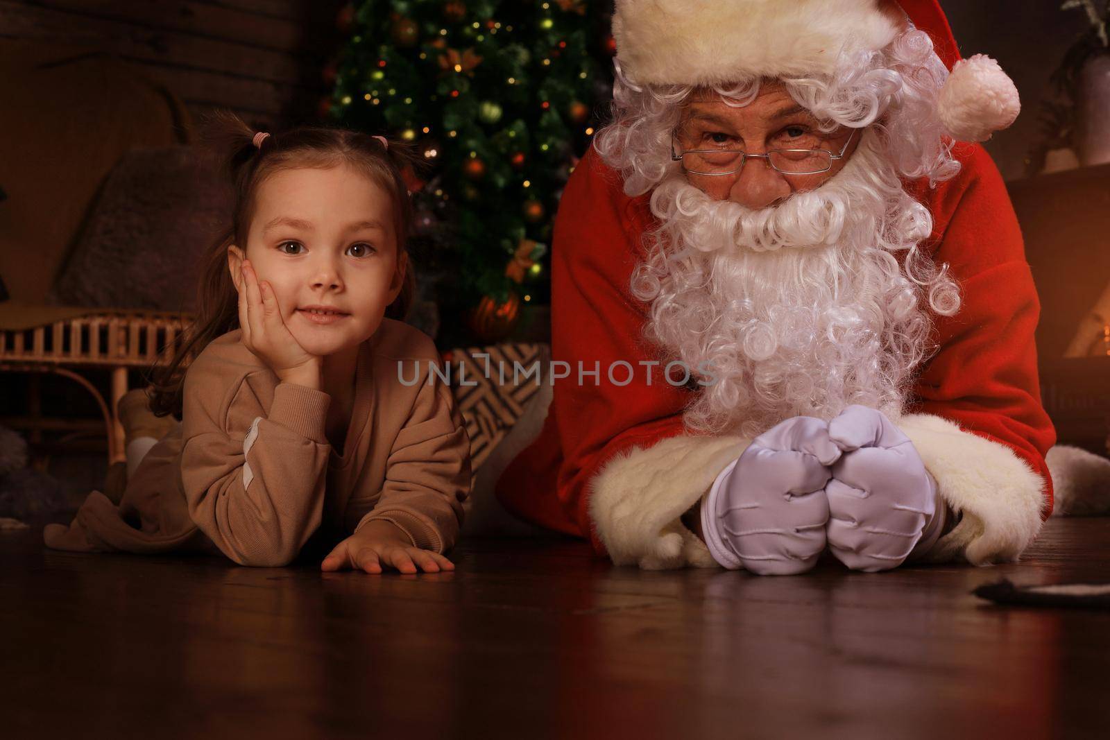 Santa Claus and child laying on floor at home. Christmas gift. Family holiday concept. by tsyhun