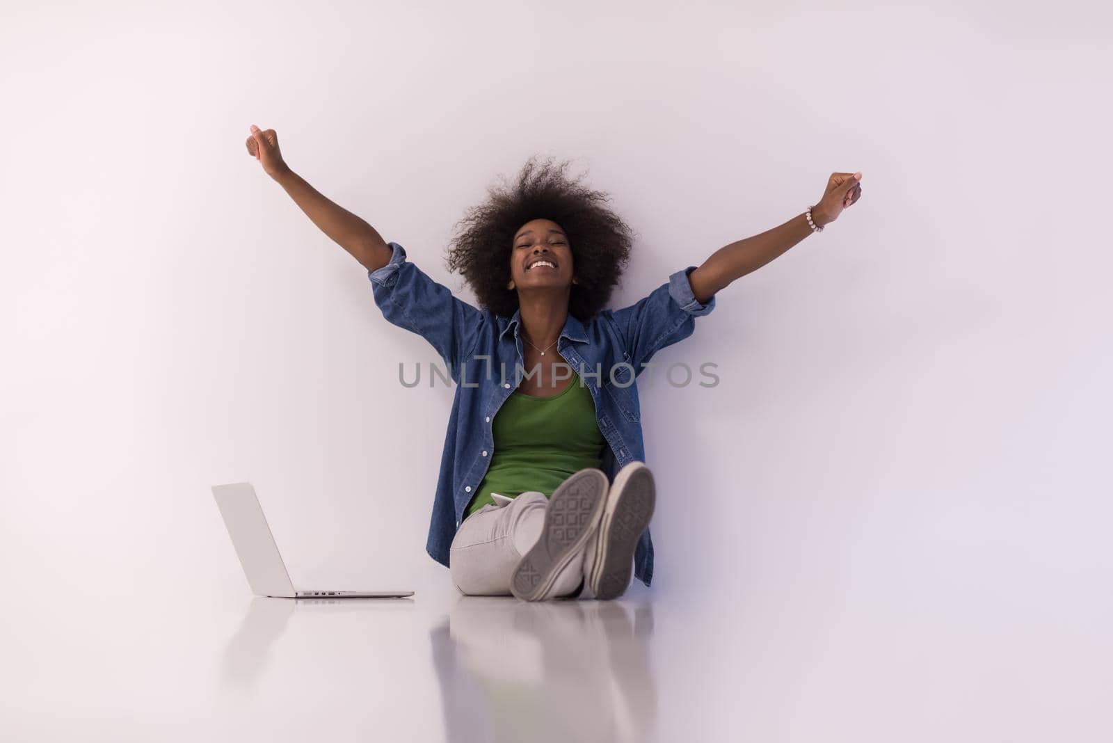 Portrait of happy young african american woman sitting on floor with laptop