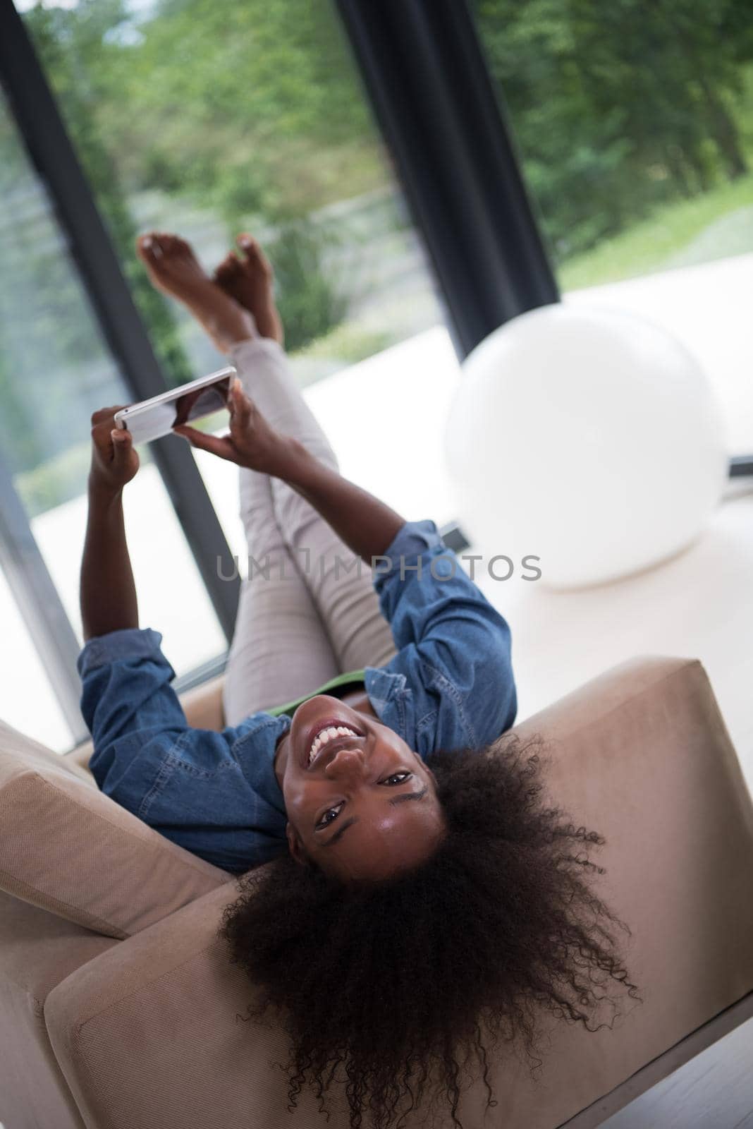 Young african american woman at home relaxing in her luxury lliving room reading a digital tablet PC surf internet and work