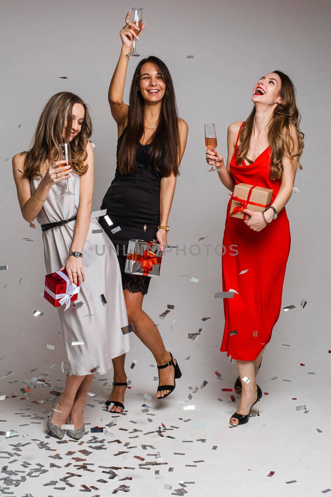 Happy pretty girlfriends enjoying party with confetti while holding champagne glasses. Party concept