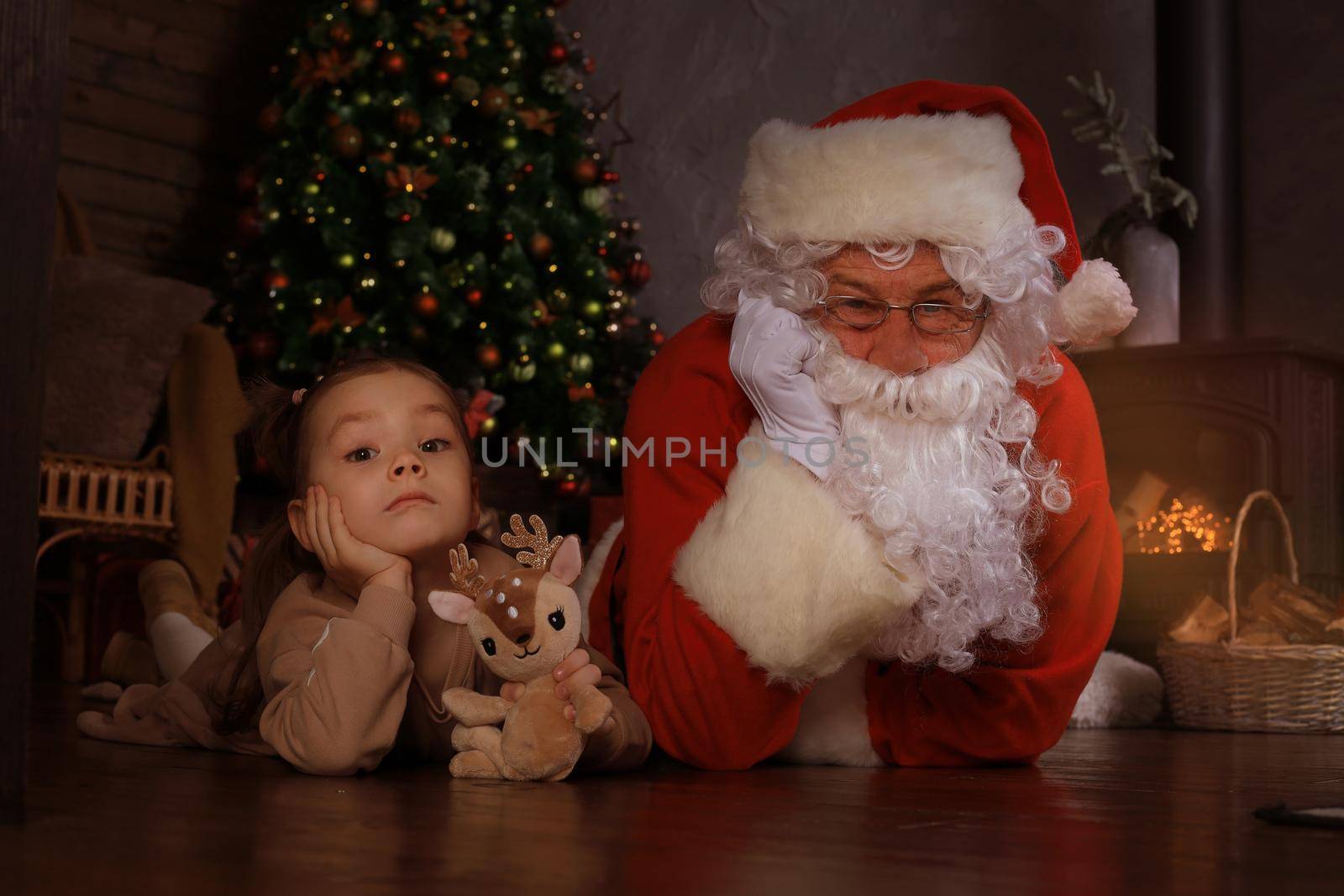 Santa Claus and child laying on floor at home. Christmas gift. Family holiday concept. by tsyhun
