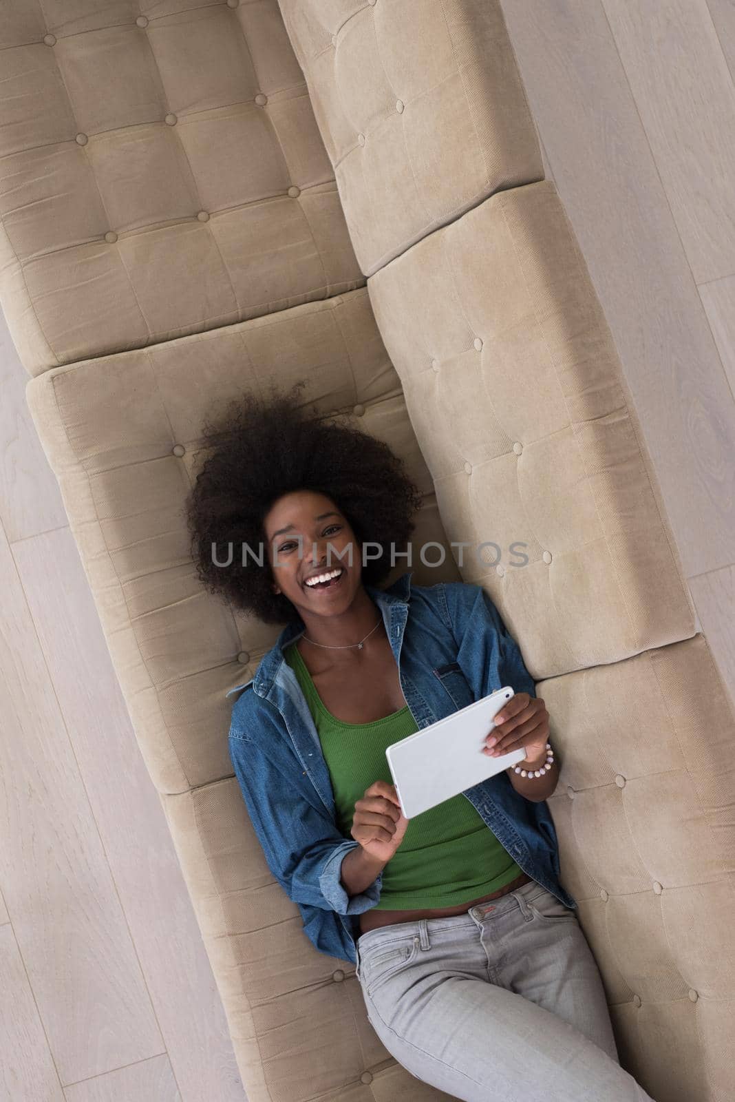 Young african american woman at home relaxing in her luxury lliving room reading a digital tablet PC surf internet and work top view