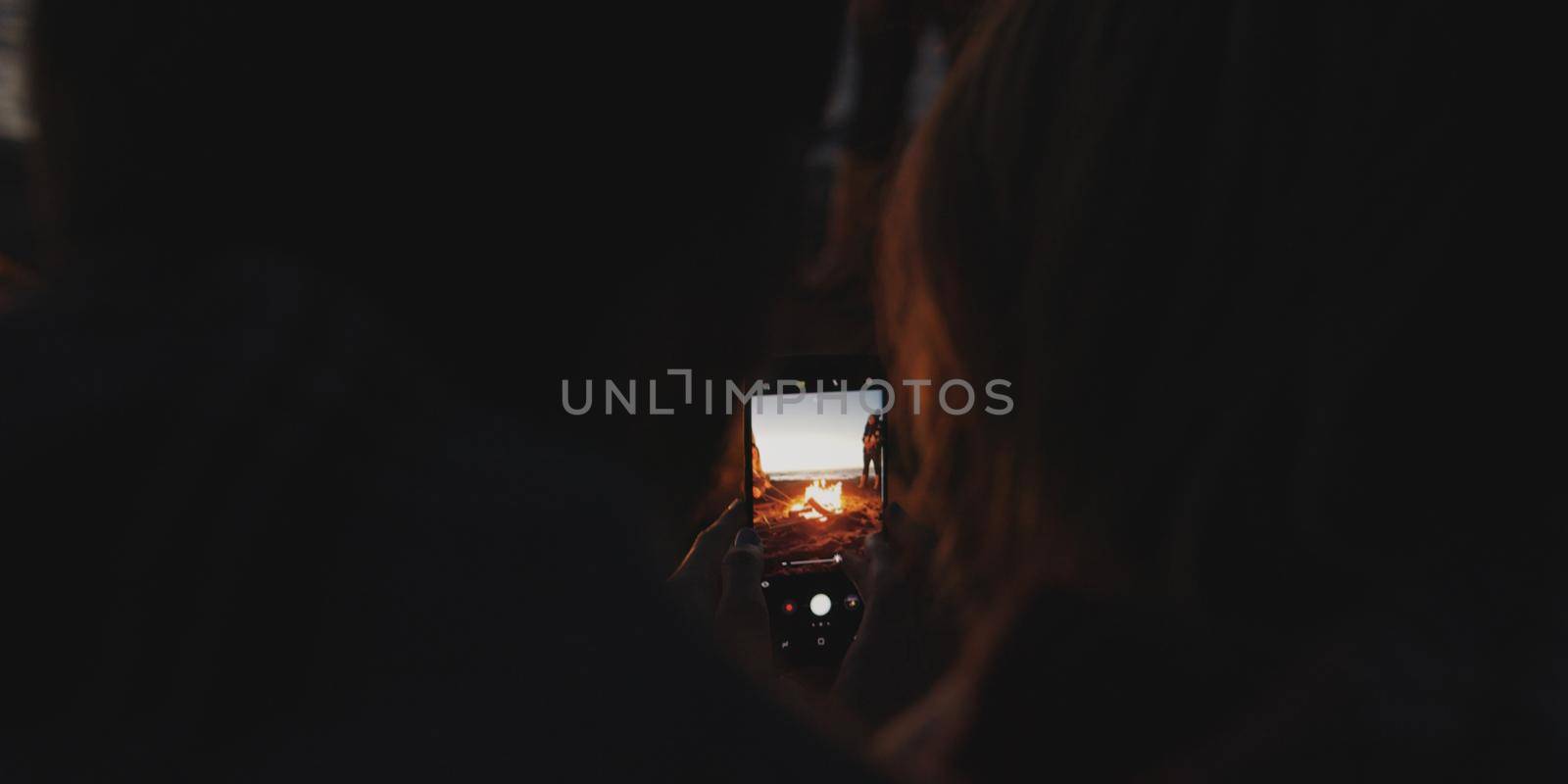 Couple taking photos beside campfire on beach by dotshock