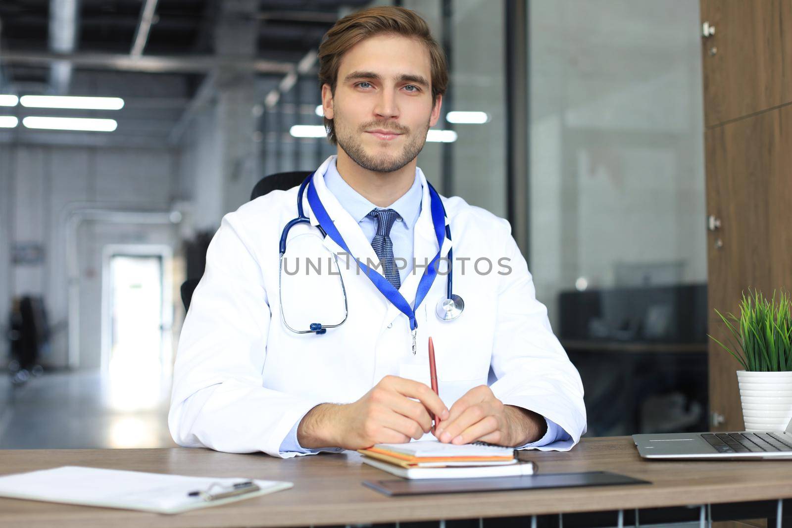 Smiling handsome male doctor talking at camera with patient. by tsyhun