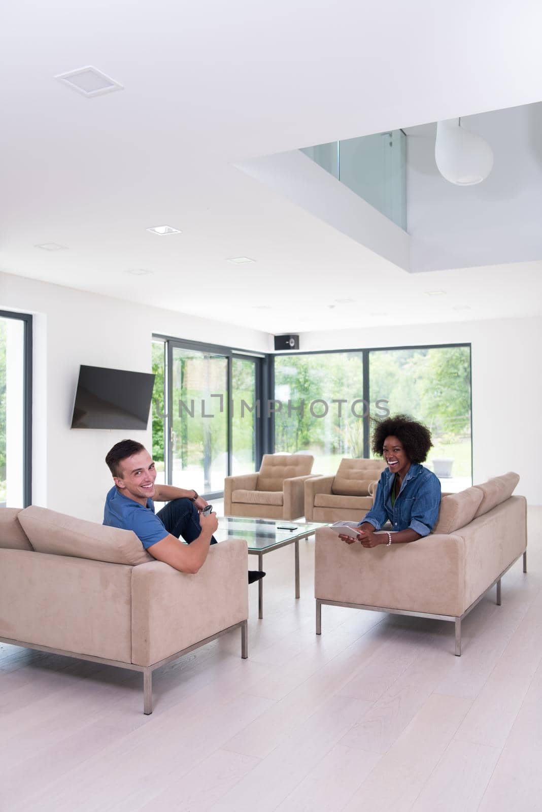 Young multiethnic couple sitting on a sofa in the luxury living room, using a tablet computer