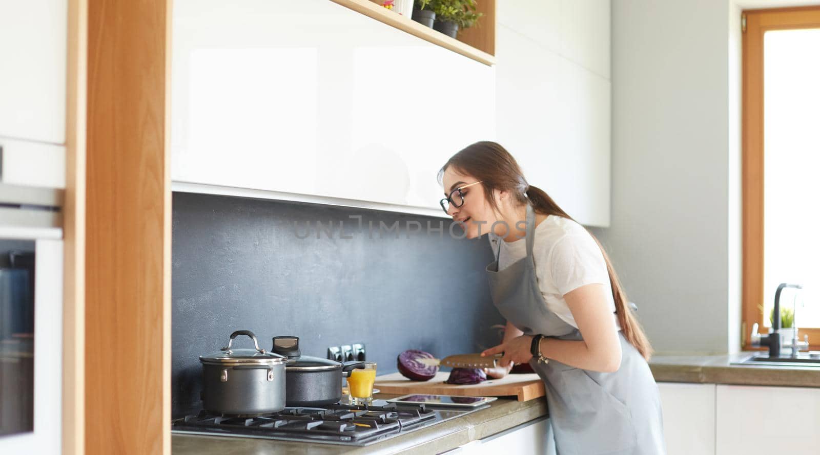 Young woman using a tablet computer to cook in her kitchen.