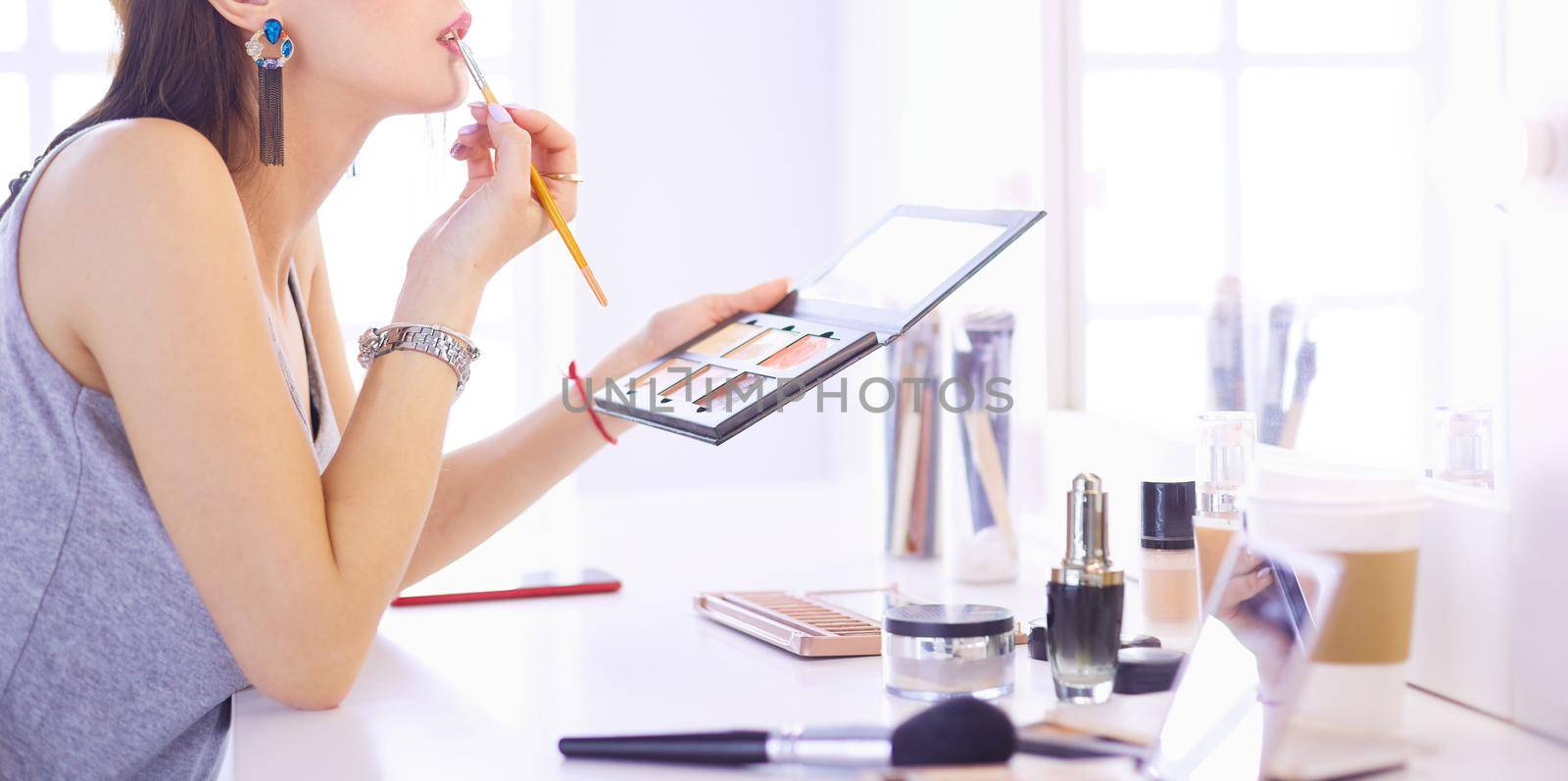 Brunette woman applying make up for a evening date in front of a mirror.