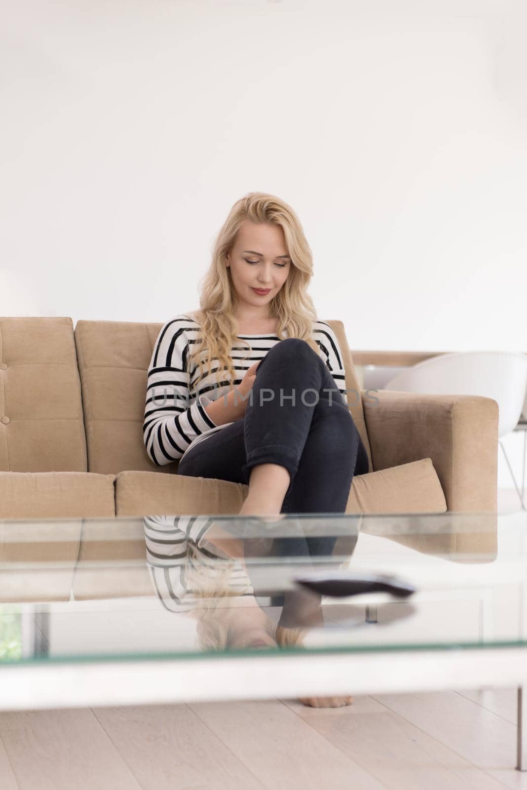 woman sitting on sofa with mobile phone by dotshock