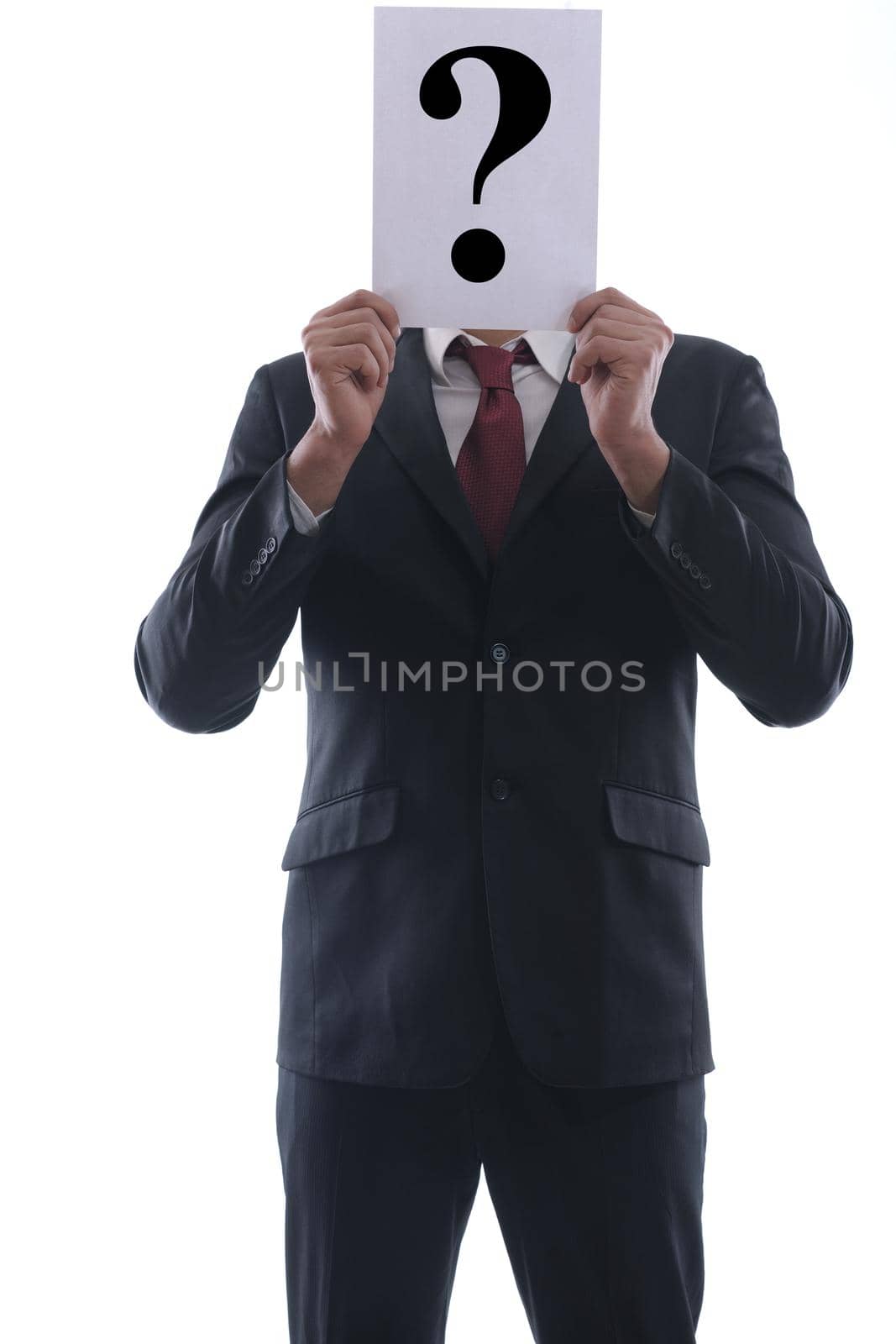 Business man holding a piece of paper over his face with a question mark on it isolated on white background in studio