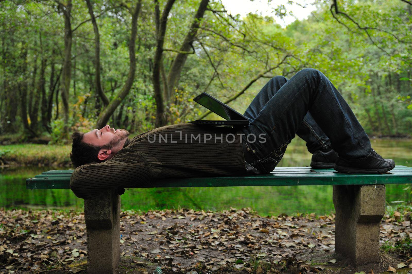 one young businessman working on laptop outdoor with green nature in background