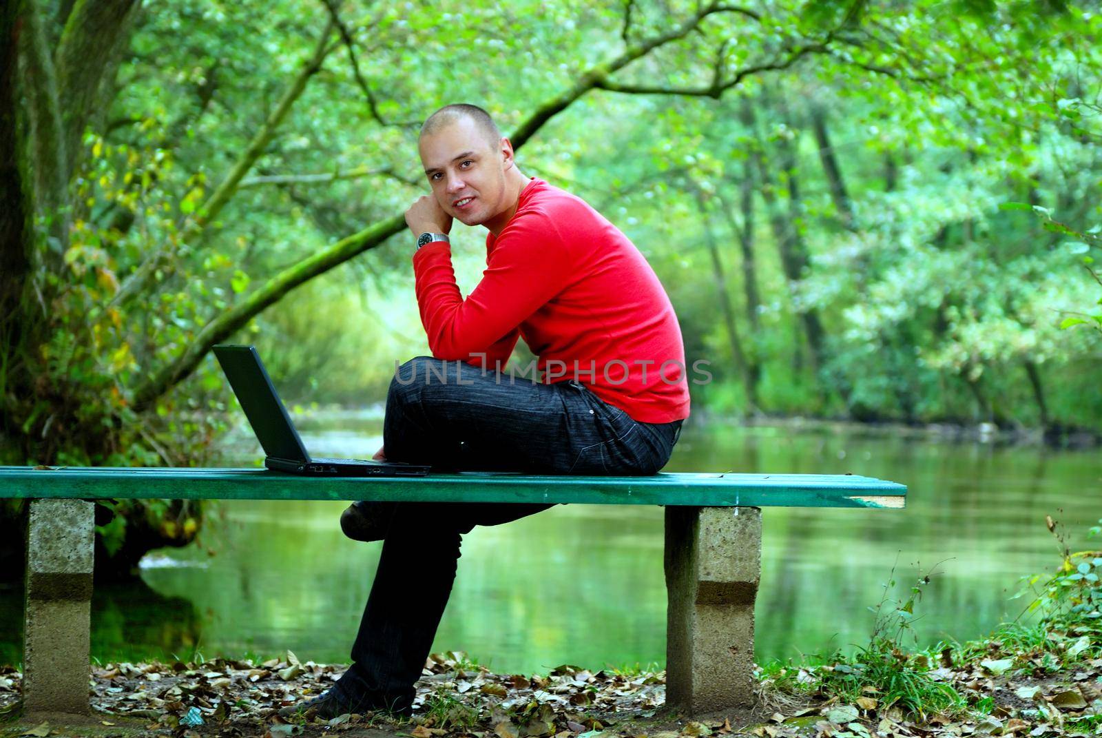 one young businessman working on laptop outdoor with green nature in background