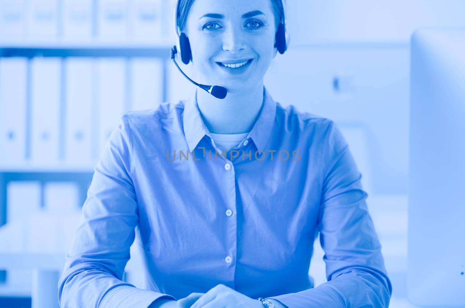 Serious pretty young woman working as support phone operator with headset in office.