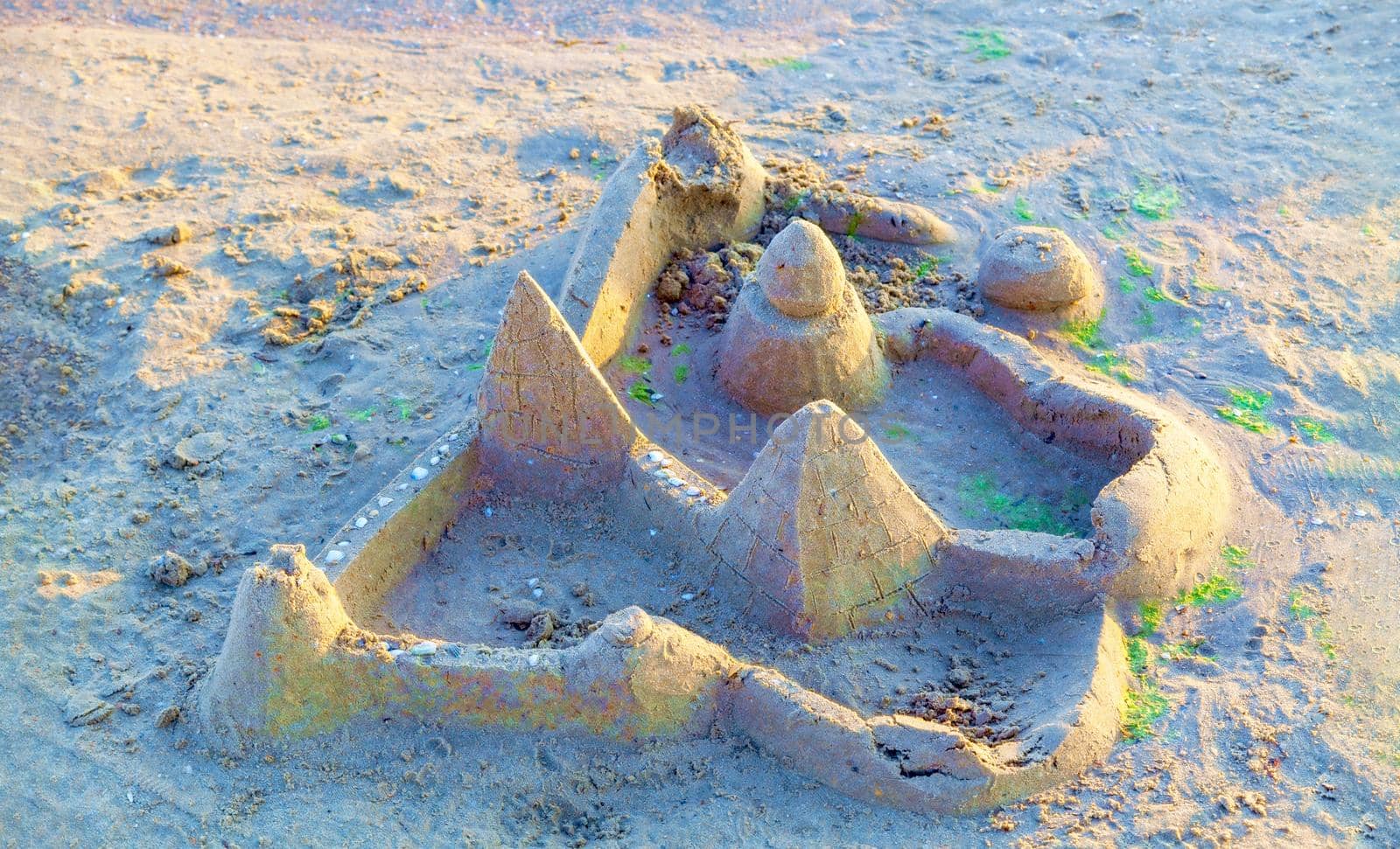 Beautiful sand castle illuminated by the morning sun on the beach of the tropical sea. The concept of a family vacation at sea.