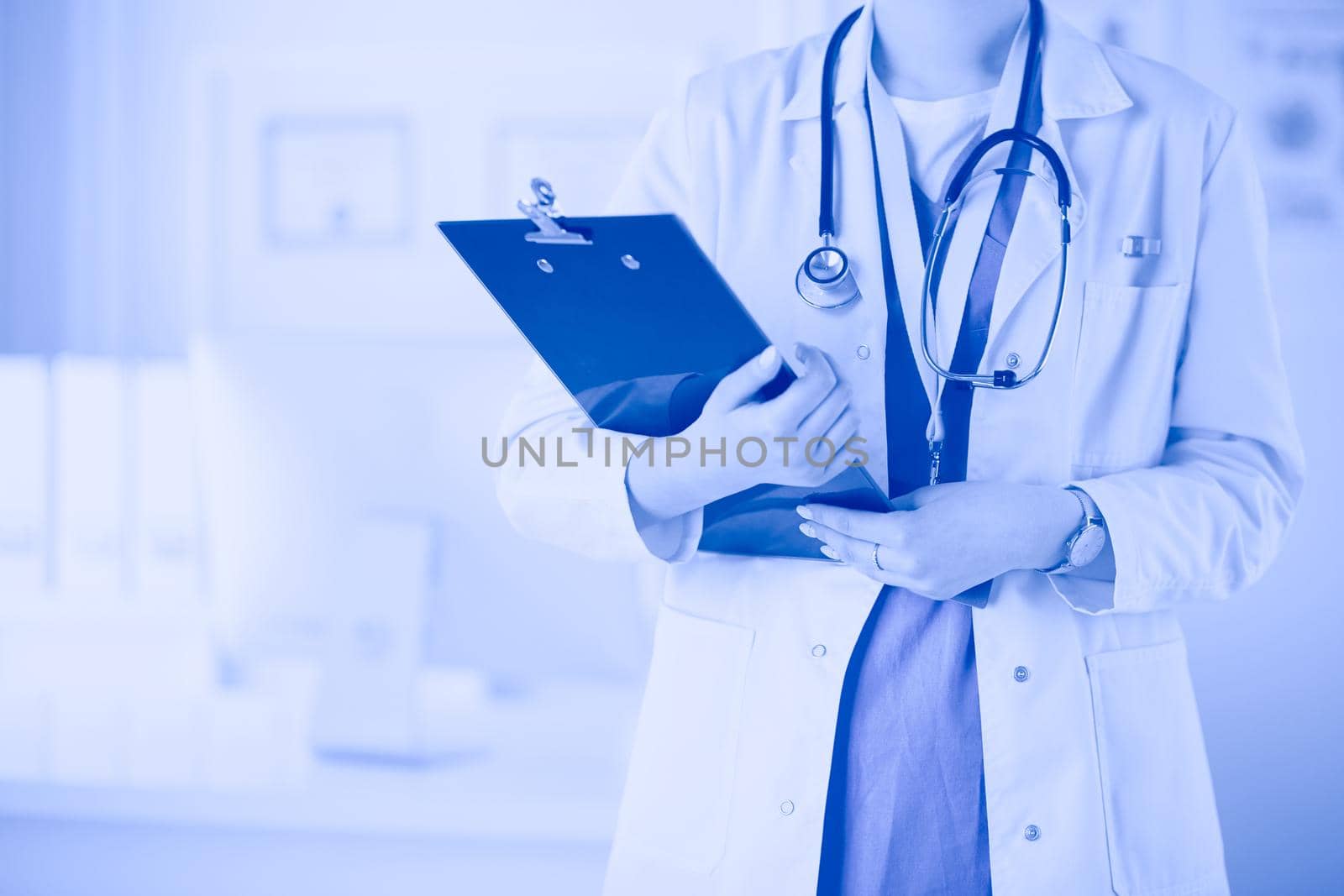 Smiling female doctor with a folder in uniform standing.