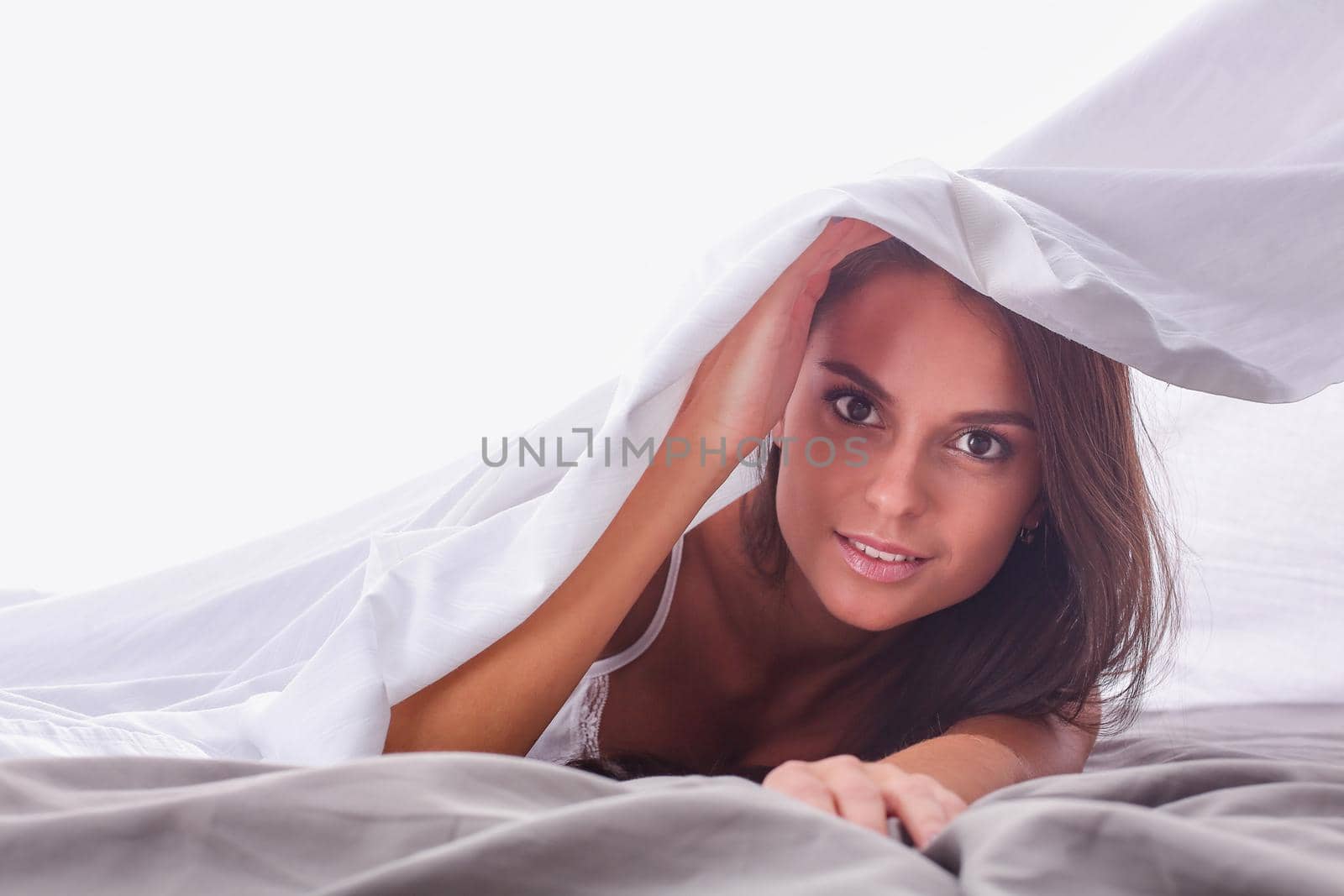 Young beautiful woman lying in bed under cover.