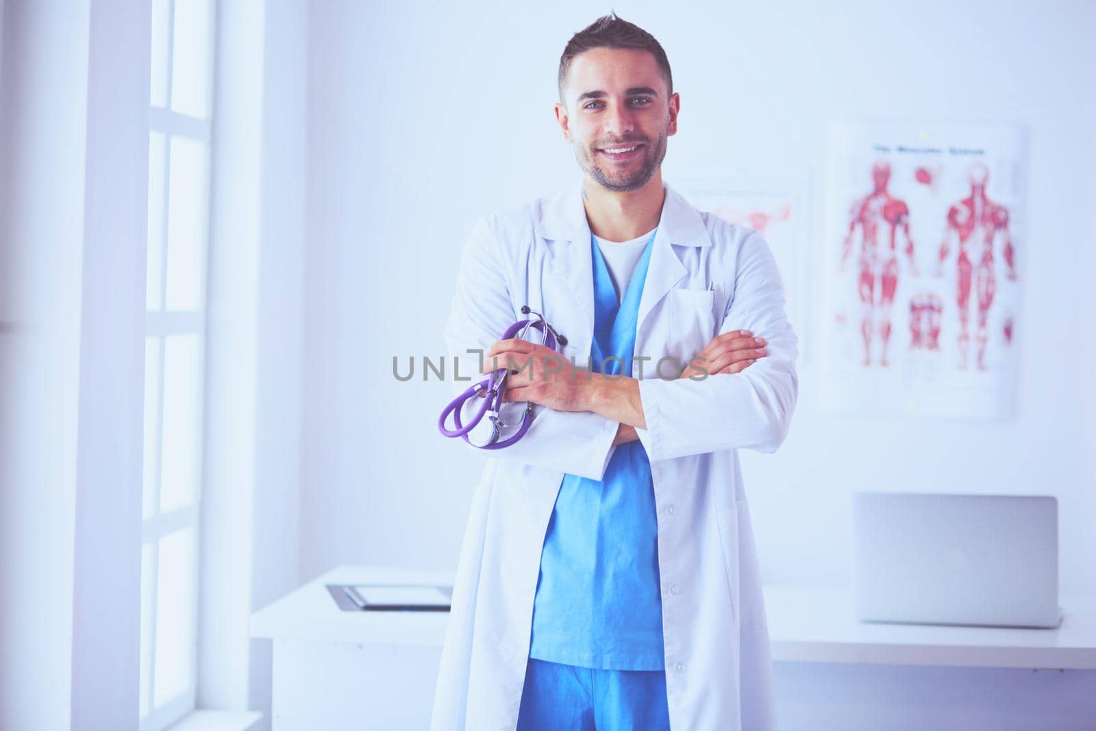 Young and confident male doctor portrait standing in medical office