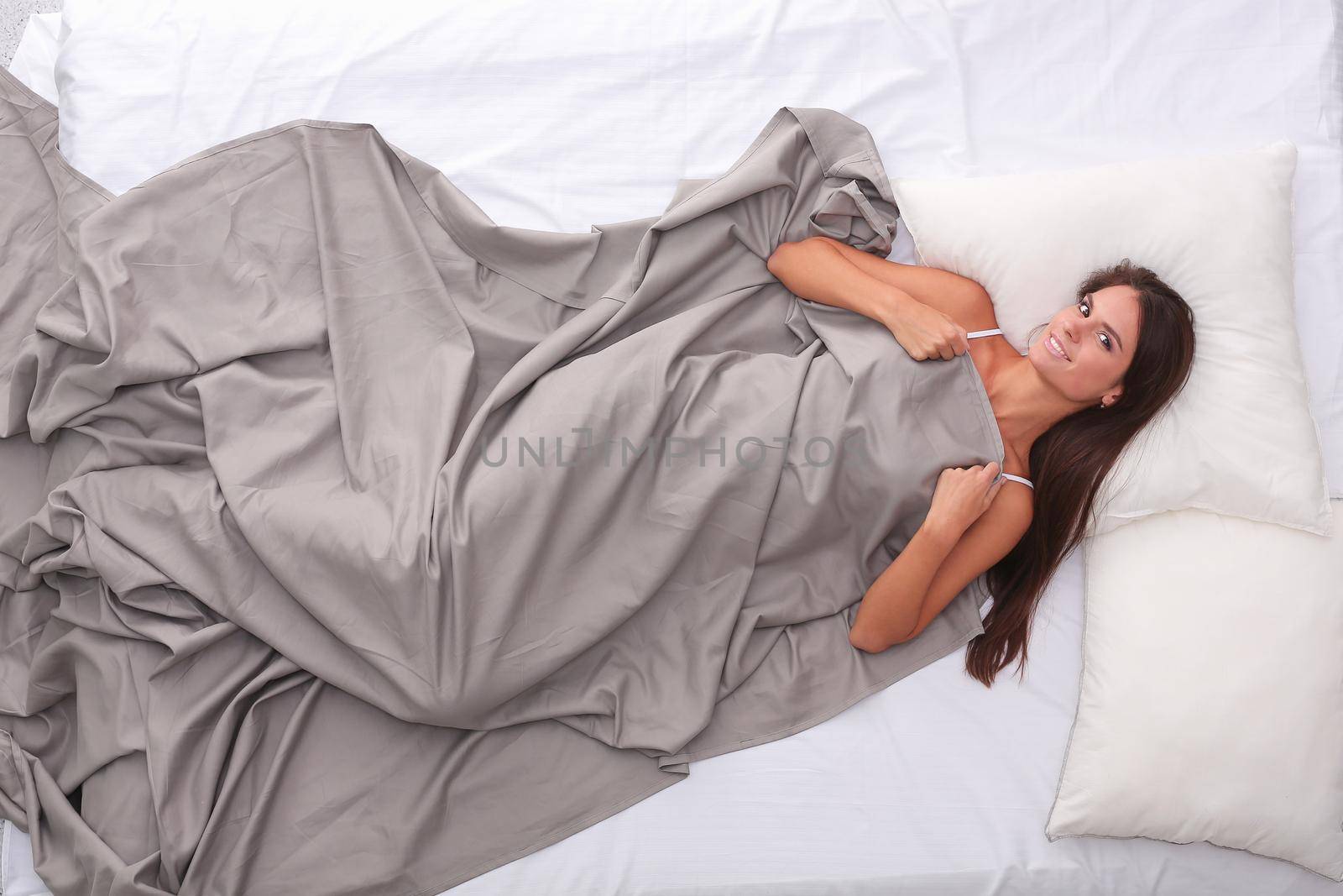 Beautiful brunette lying on bed at home.