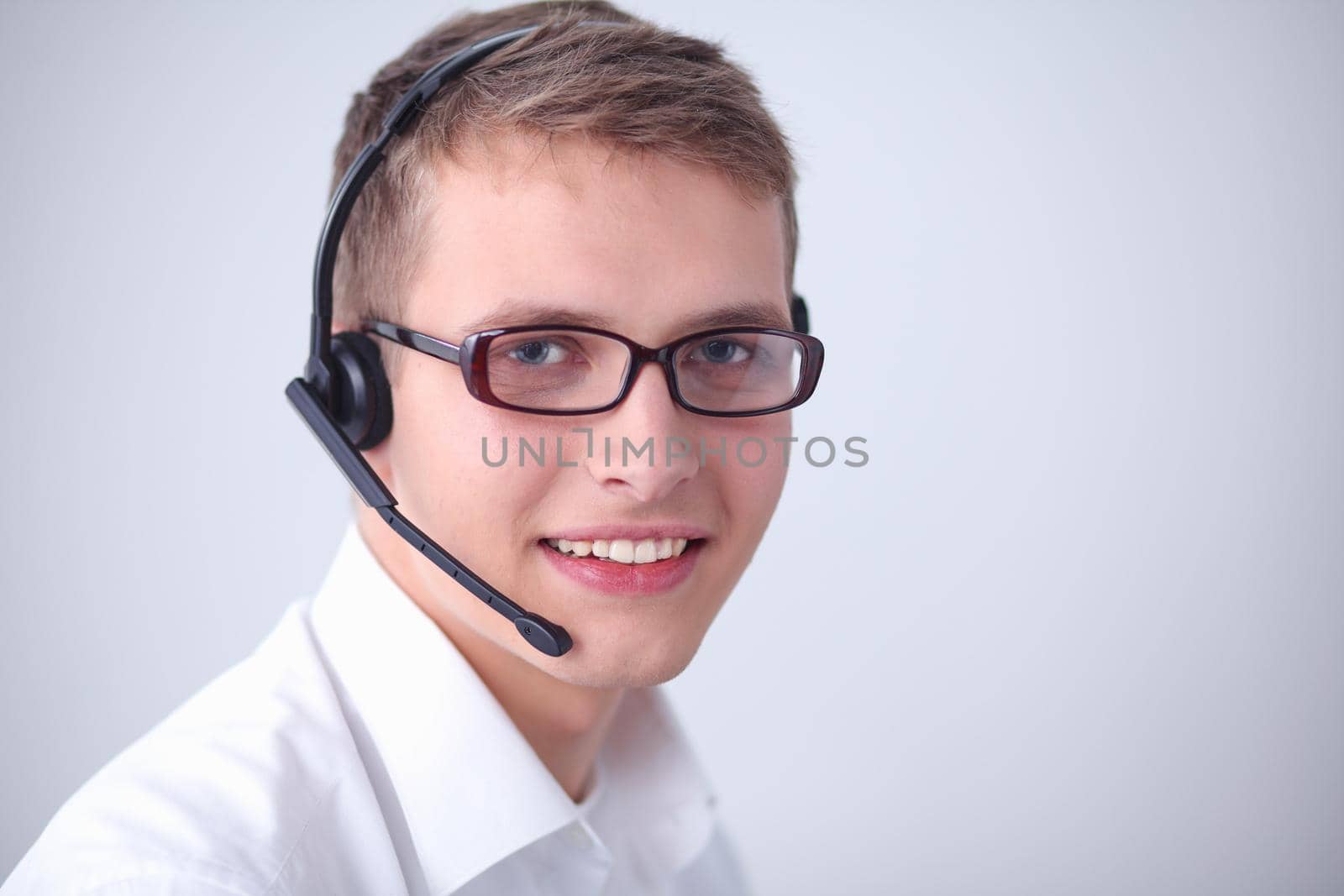 Portrait of young man smiling sitting on gray background. Portrait of young man .