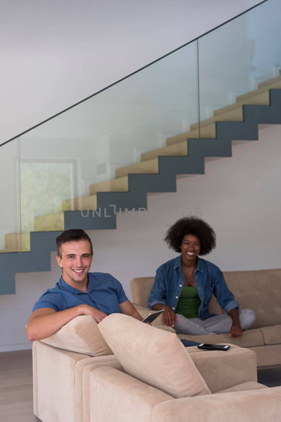 multiethnic couple relaxing at  home with tablet computers by dotshock