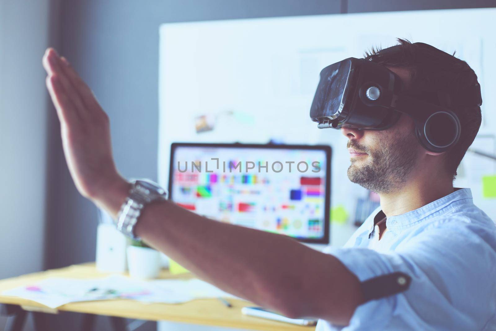 Young male software programmer testing a new app with 3d virtual reality glasses in office