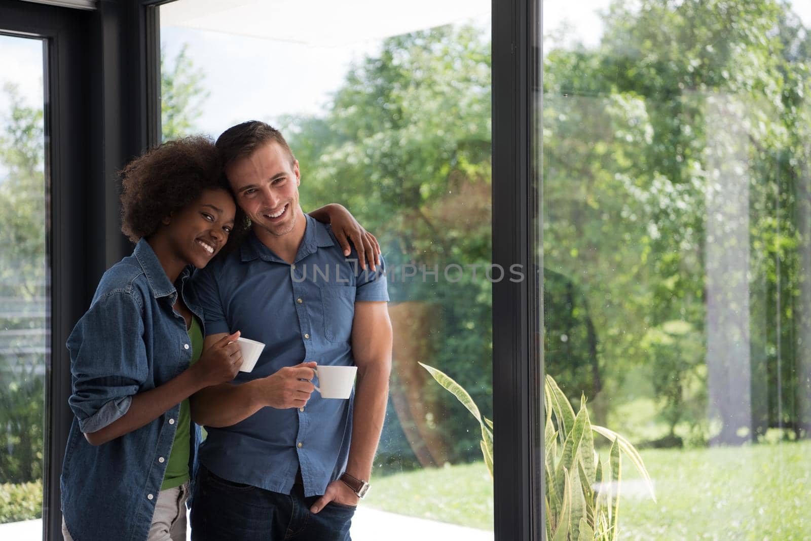 romantic happy young multiethnic couple enjoying morning coffee by the window in their luxury home