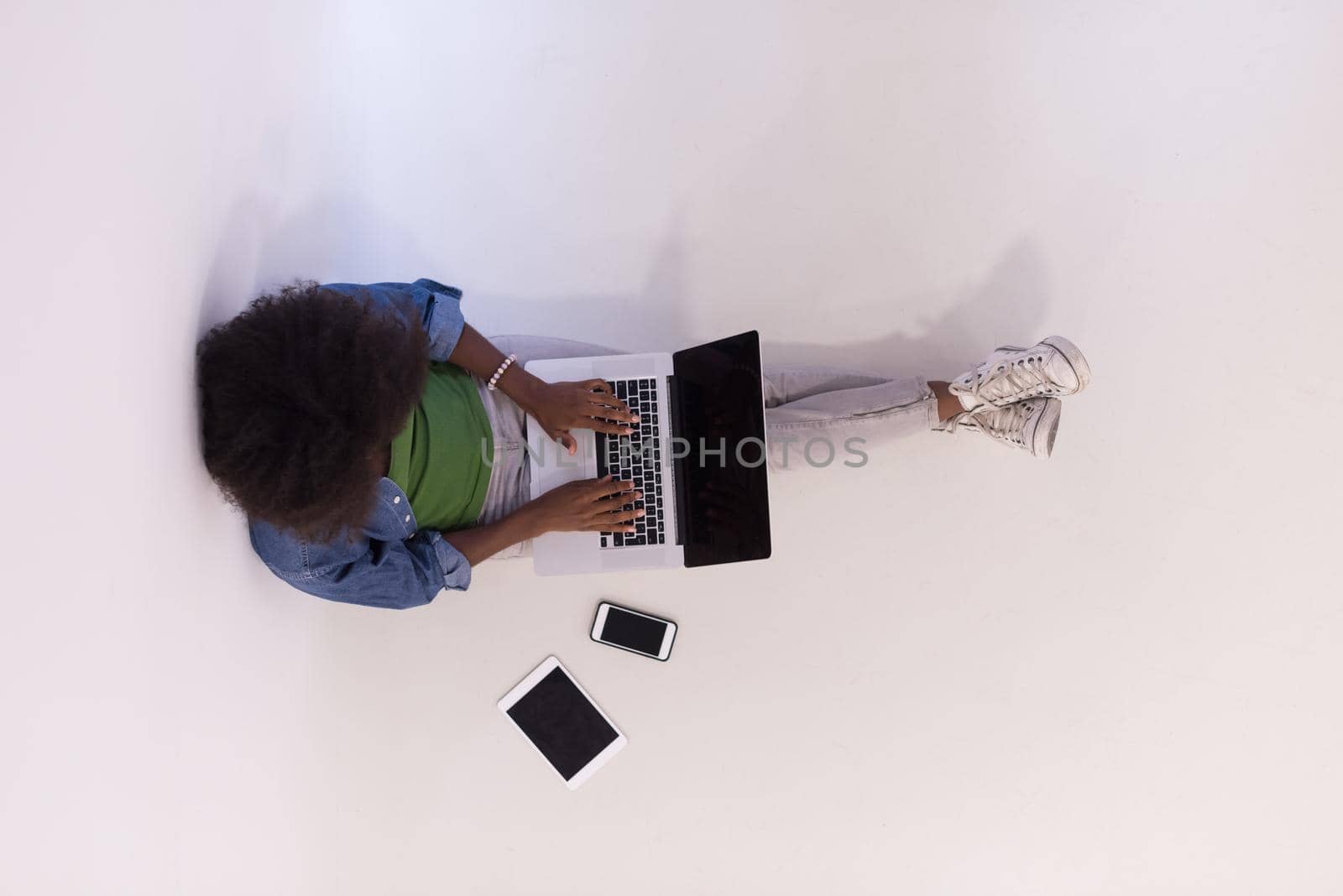 Portrait of happy young african american woman sitting on floor with laptop top view