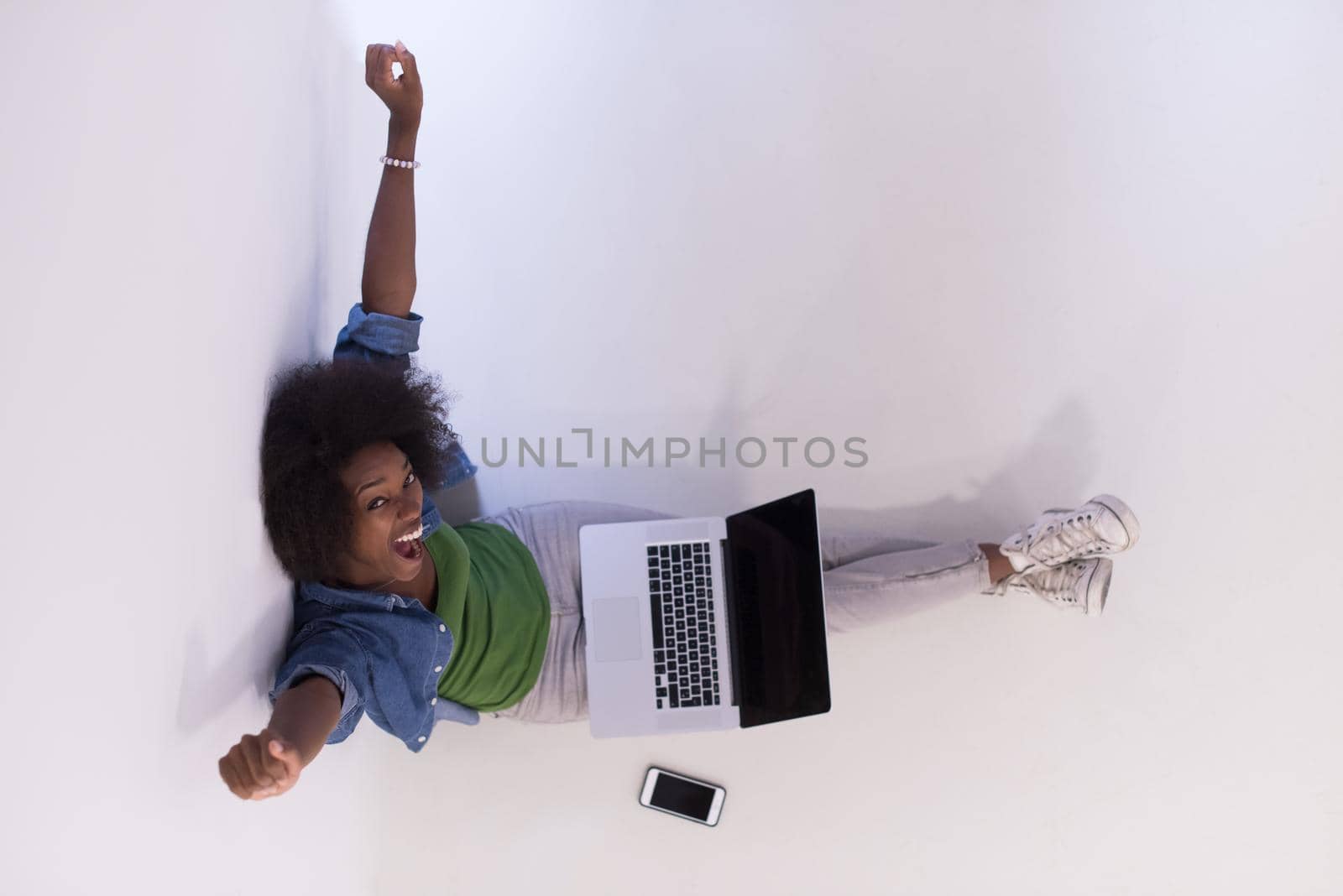 african american woman sitting on floor with laptop top view by dotshock