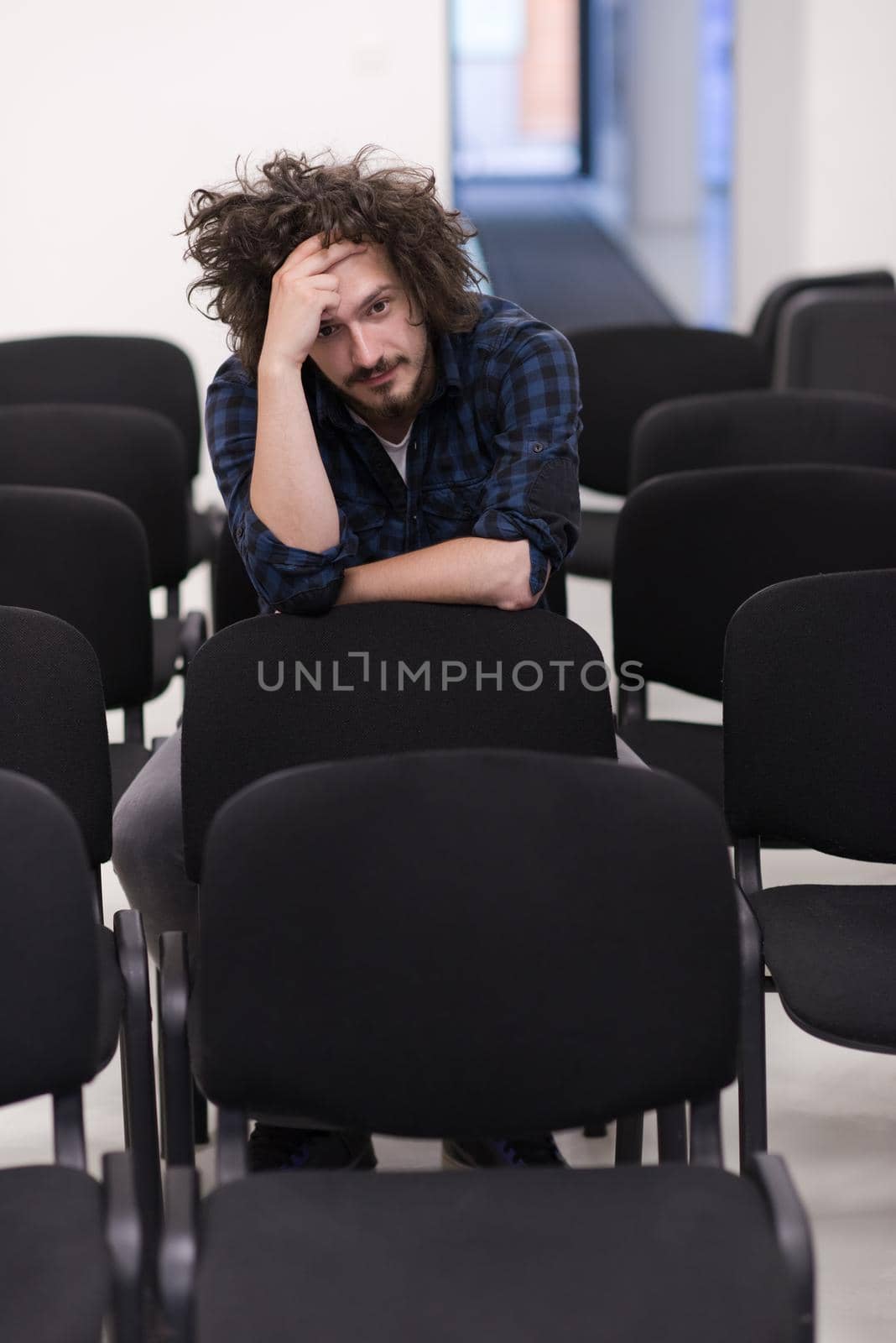 A student sits alone in a empty seats in a classroom